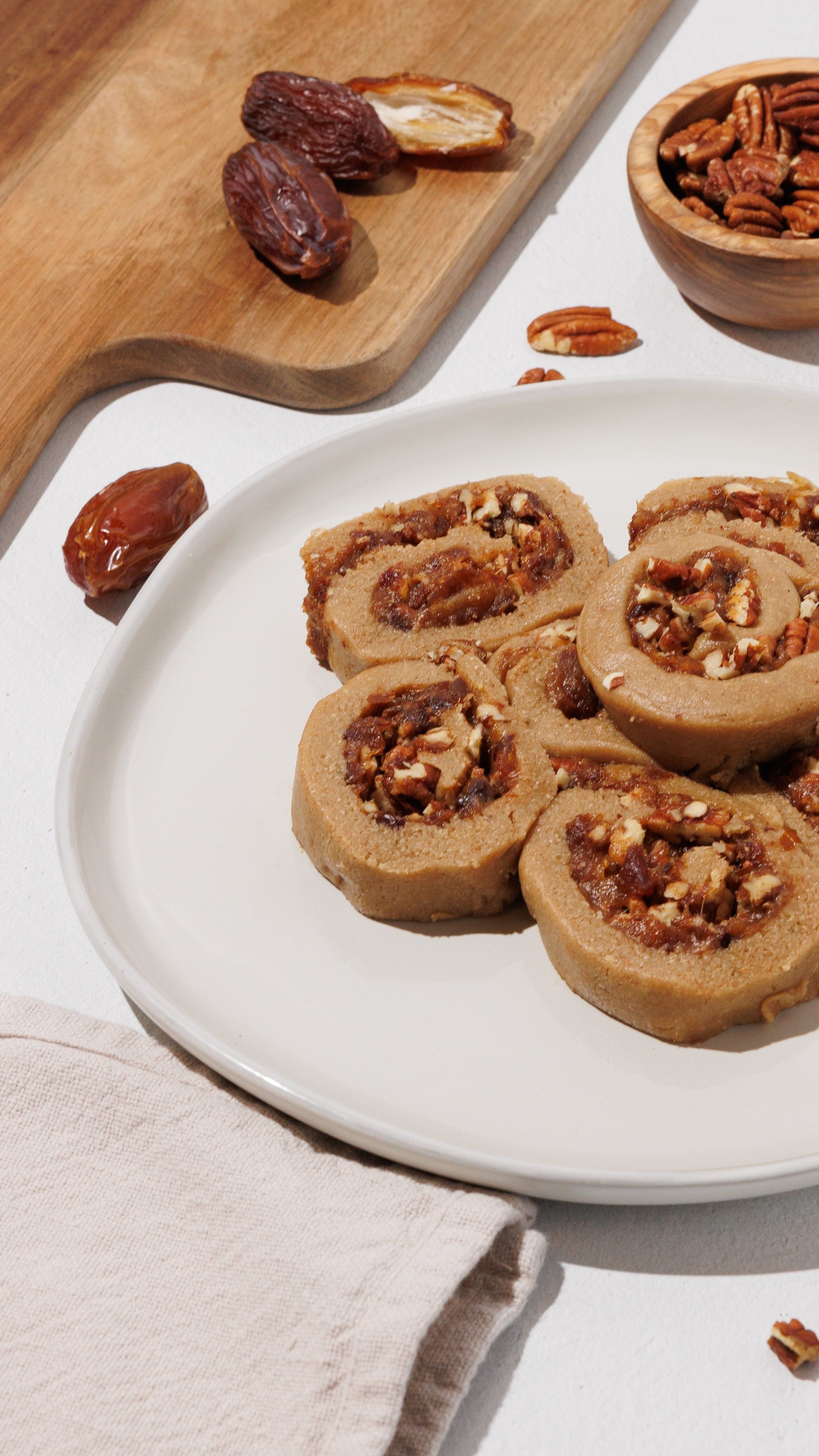 Sliced cinnamon rolls with chunky filling and chopped pecans on a white plate.