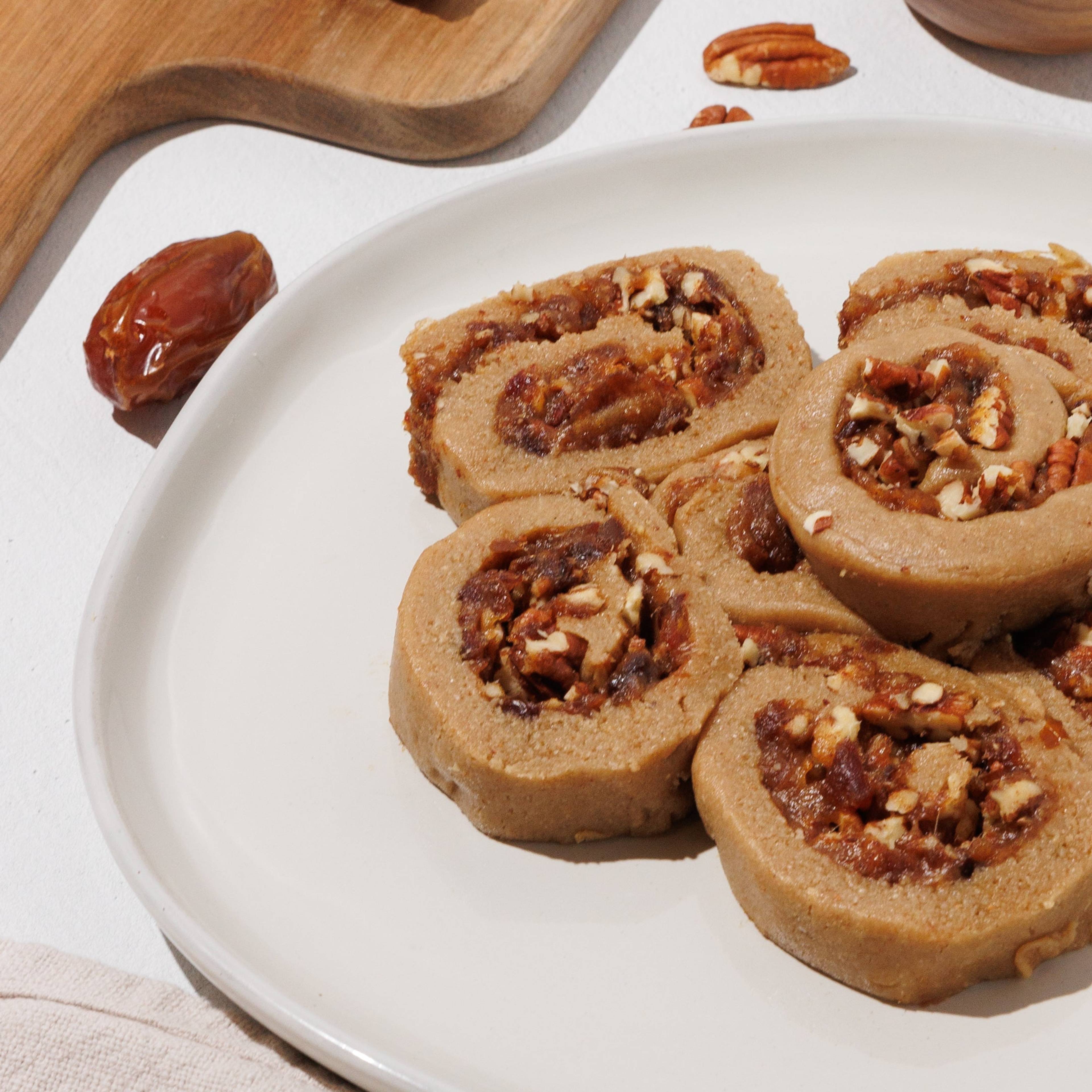 Sliced cinnamon rolls with chunky filling and chopped pecans on a white plate.