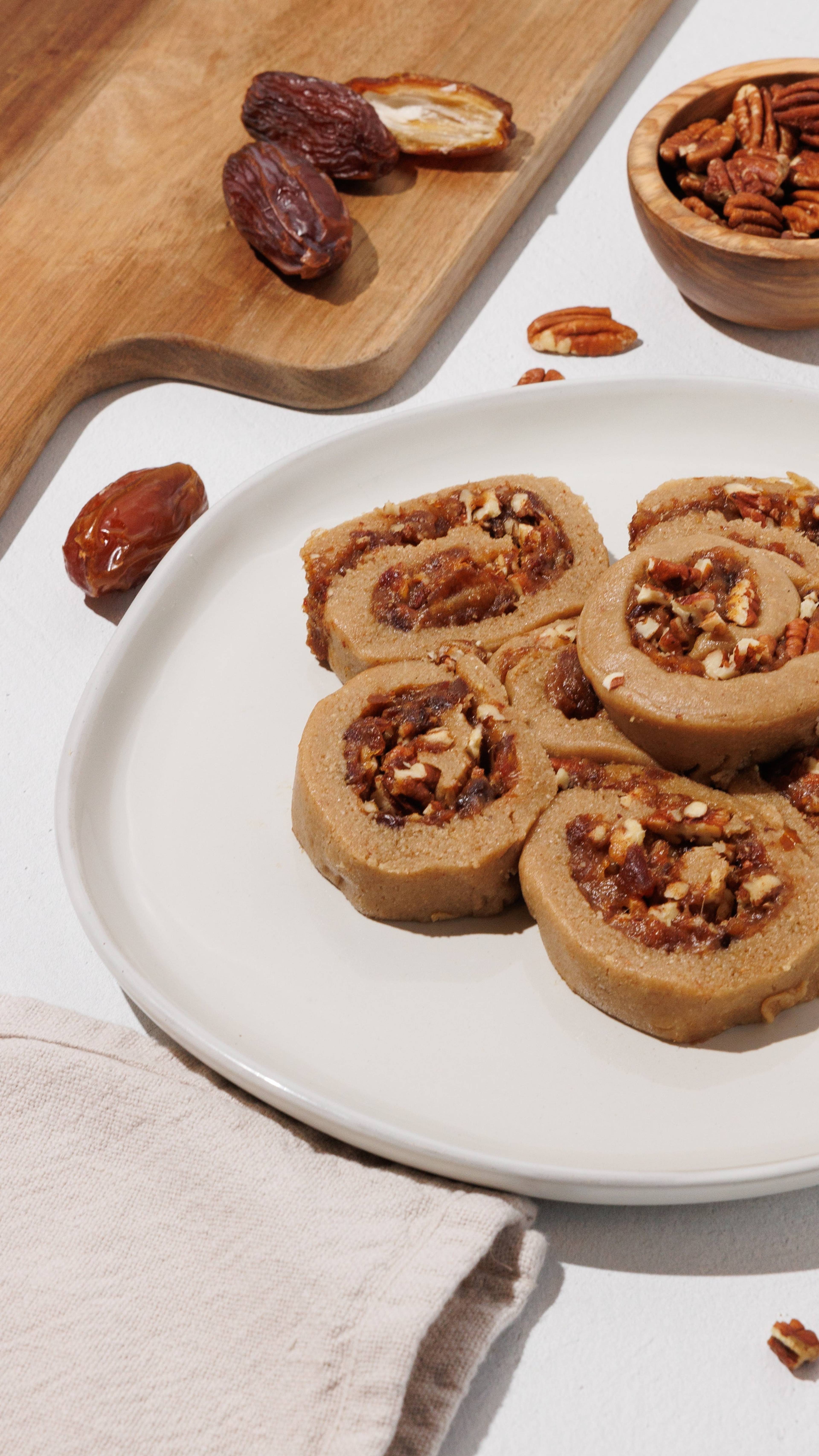 Sliced cinnamon rolls with chunky filling and chopped pecans on a white plate.
