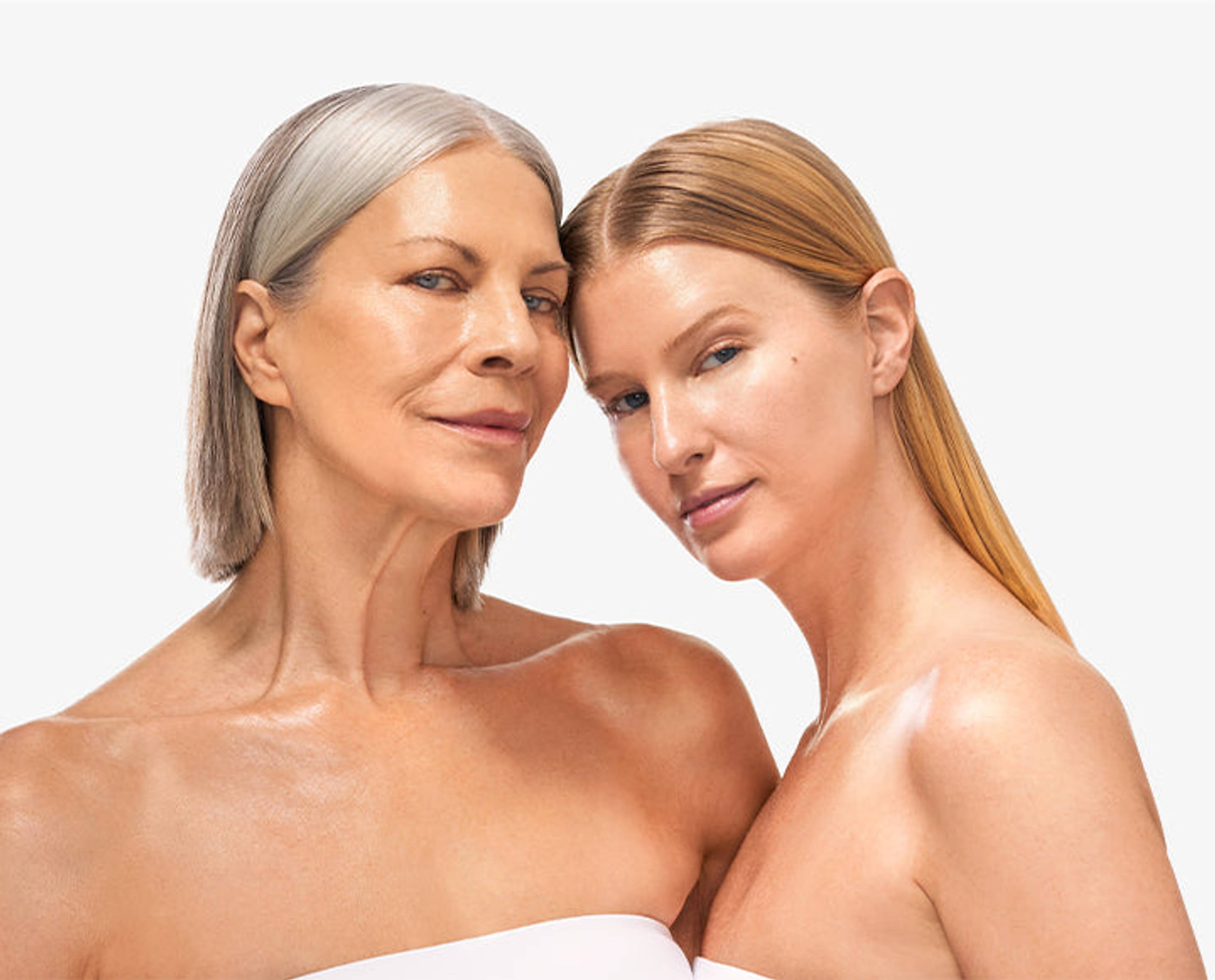 Close portrait of two women with bare shoulders against a white background.
