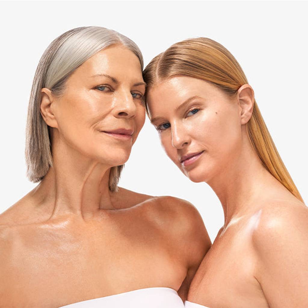 Close portrait of two women with bare shoulders against a white background.