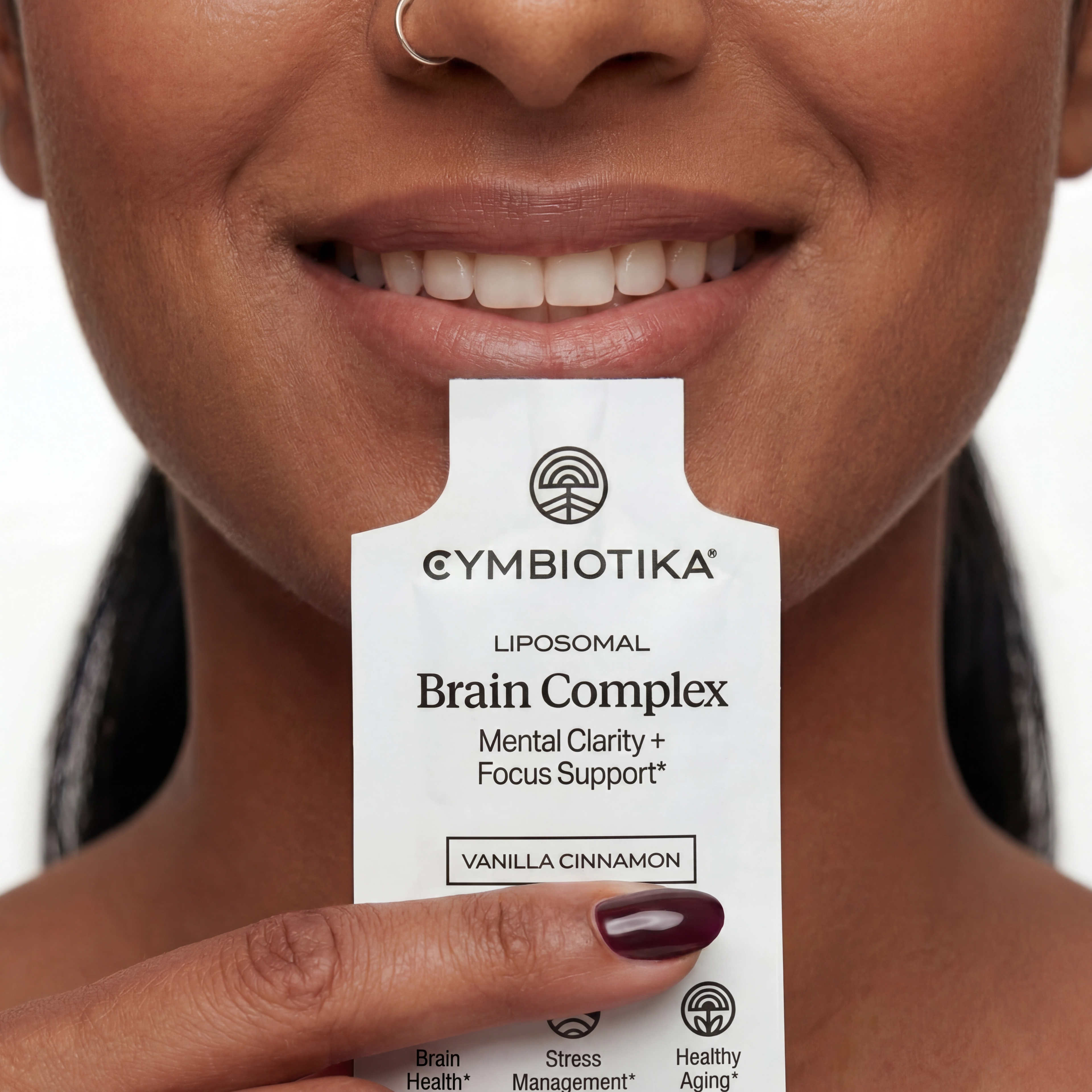 Smiling person holds a Cymbiotika Liposomal Brain Complex vanilla cinnamon packet below their mouth.