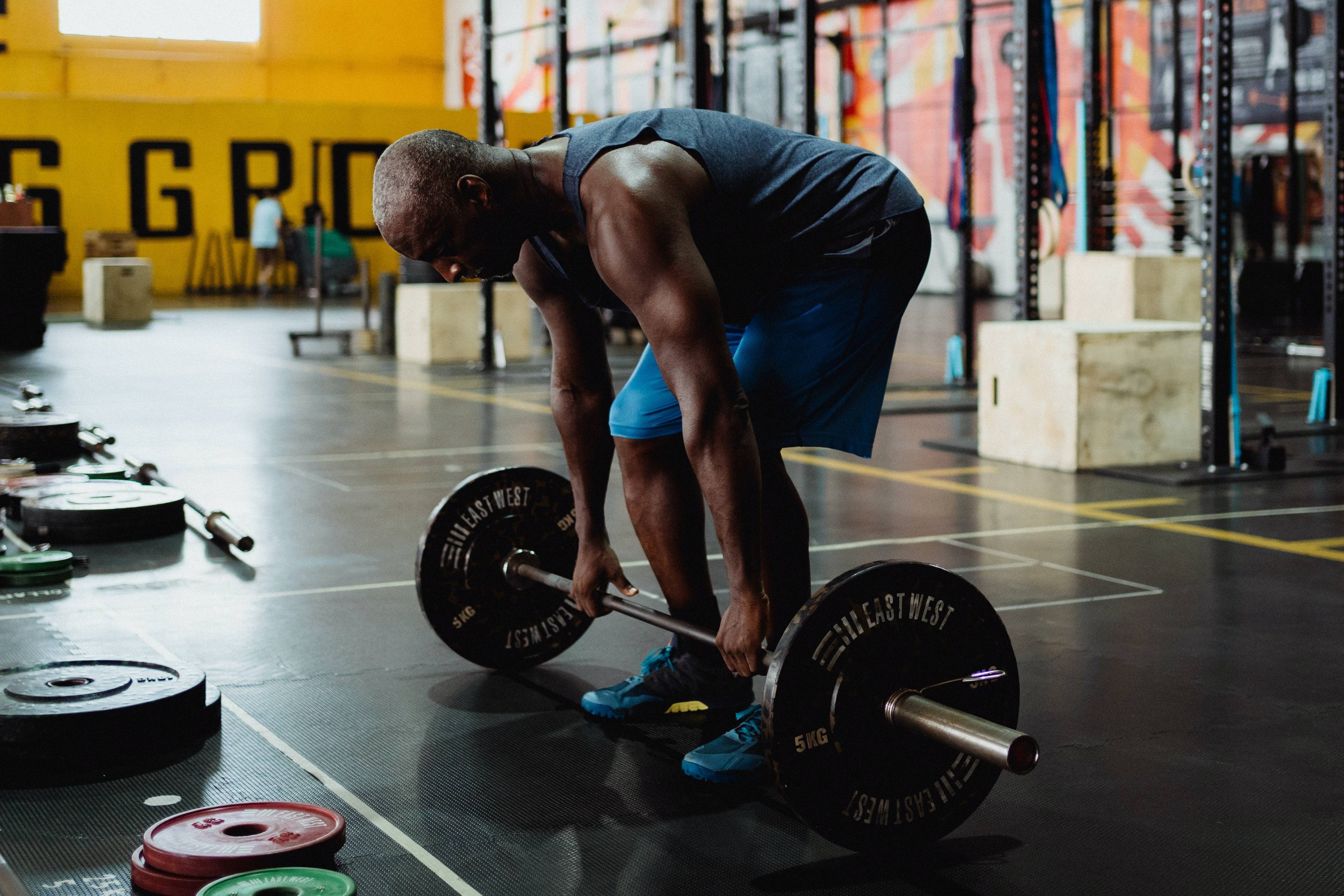 Man bending over a loaded barbell in a gym