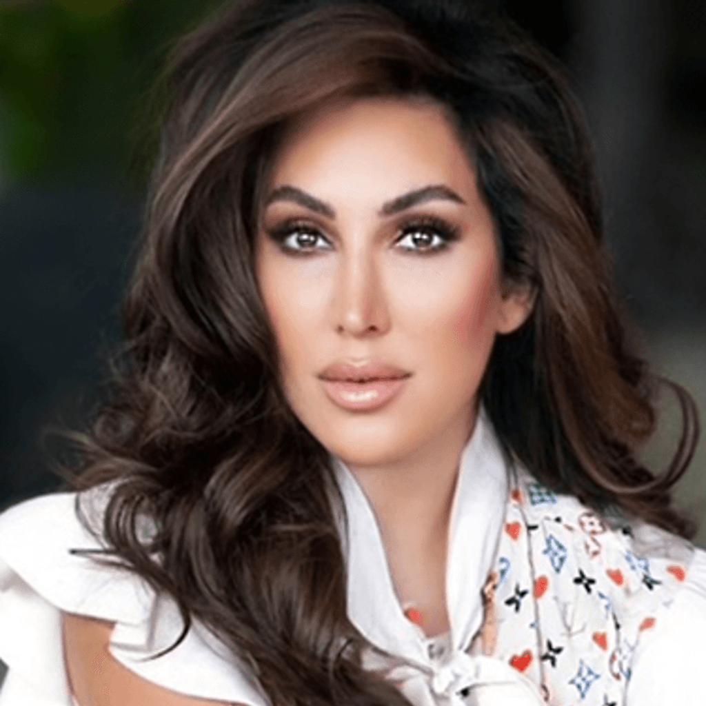Portrait of a woman with long dark wavy hair wearing a white ruffled top and patterned scarf.