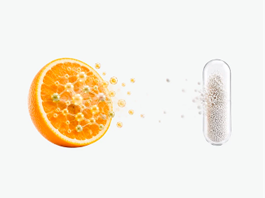 An orange slice with scattered particles beside a capsule-shaped form filled with fine particles.