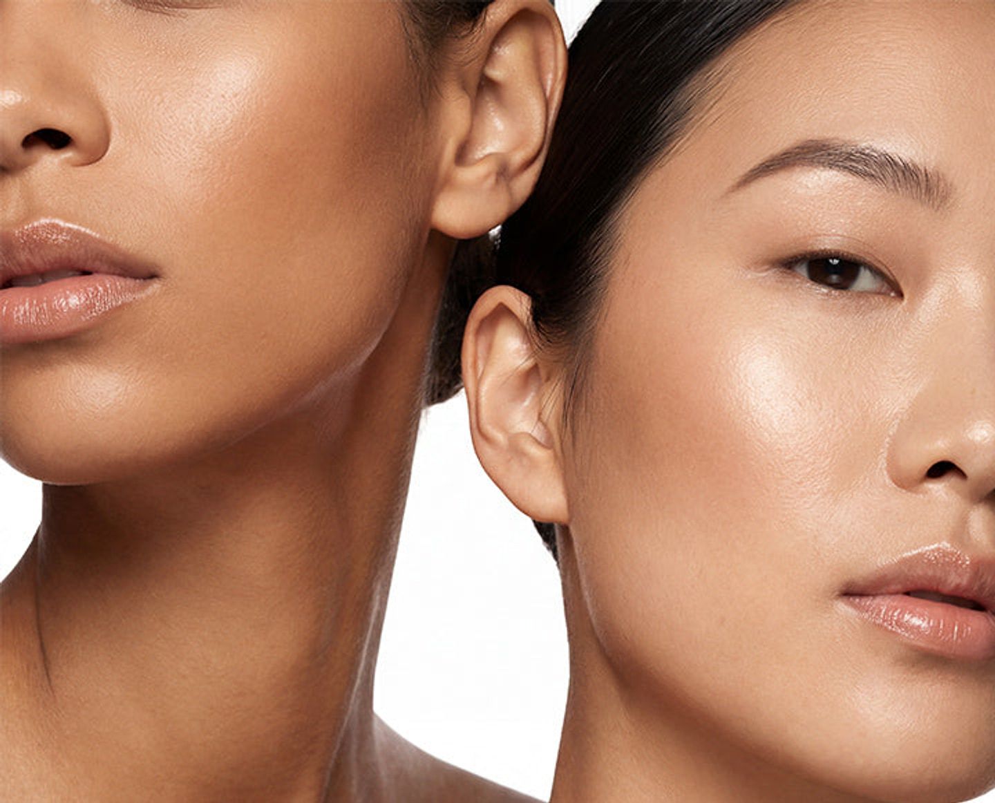 Close-up studio portrait of two women with luminous skin against a white background.