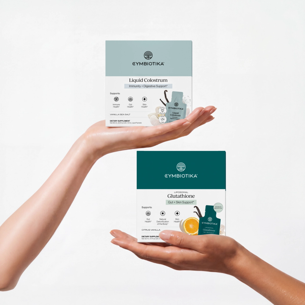 Hands present Cymbiotika Liquid Colostrum and Liposomal Glutathione supplement boxes.