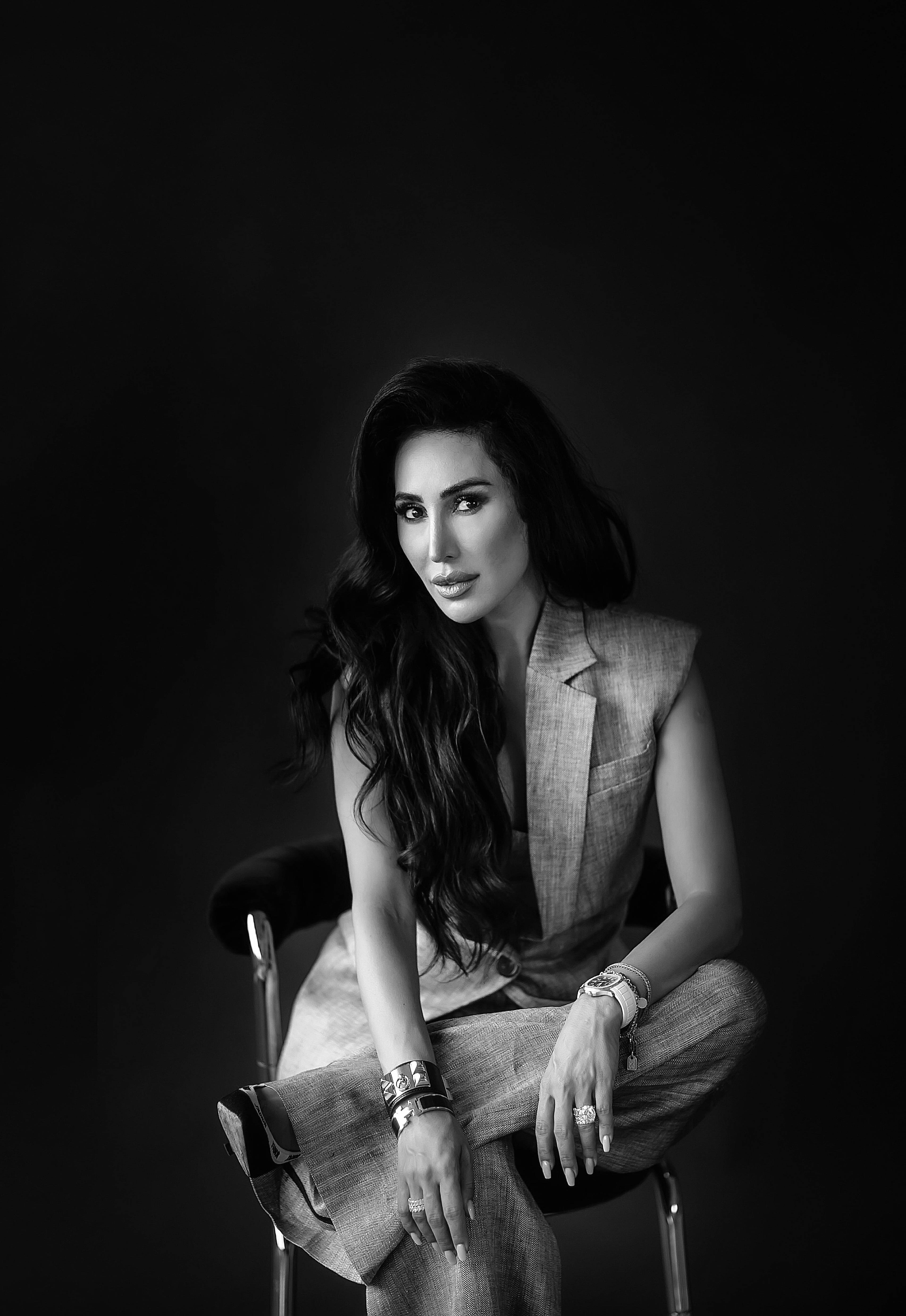 Black-and-white portrait of a woman in a sleeveless suit seated on a chair.