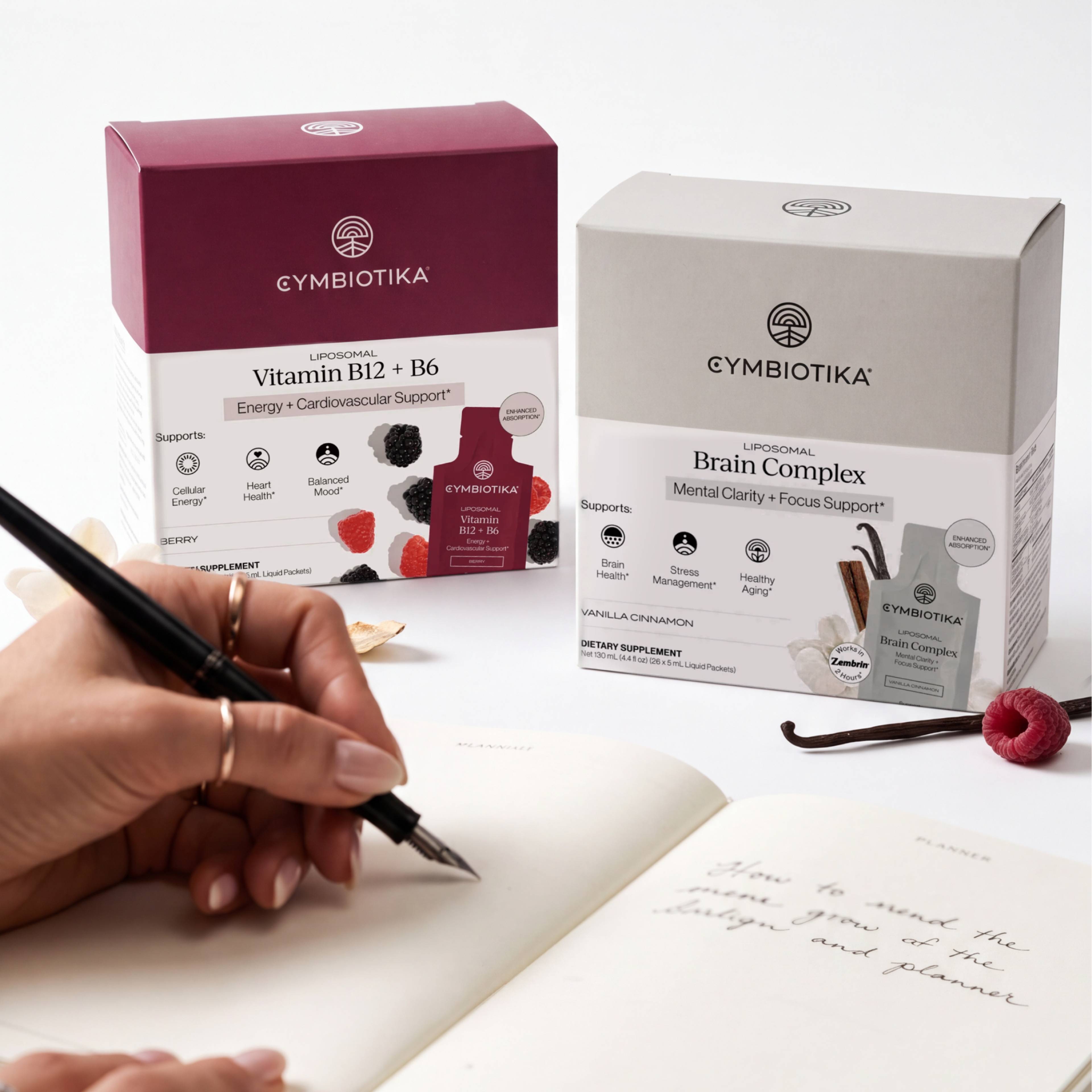 Liposomal Vitamin B12 + B6 and Liposomal Brain Complex boxes beside a hand writing in a notebook.