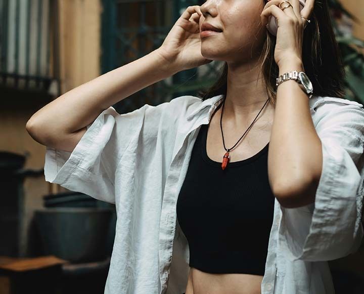 Woman in a white shirt adjusts her hair indoors.