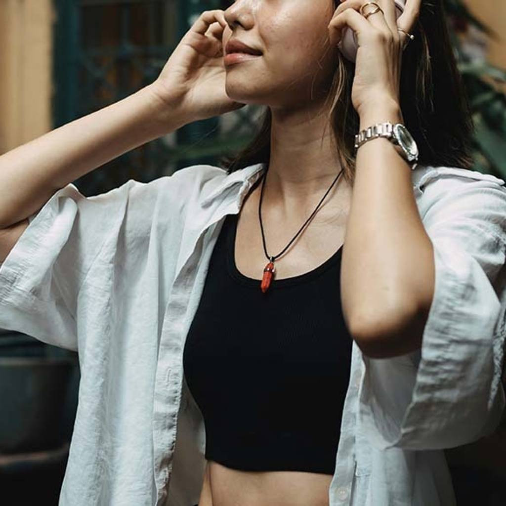 Woman in a white shirt adjusts her hair indoors.