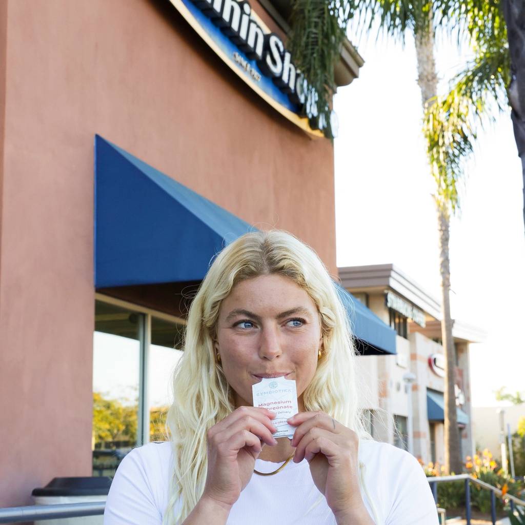 A woman holds a small Cymbiotika packet outside a Vitamin Shoppe storefront.