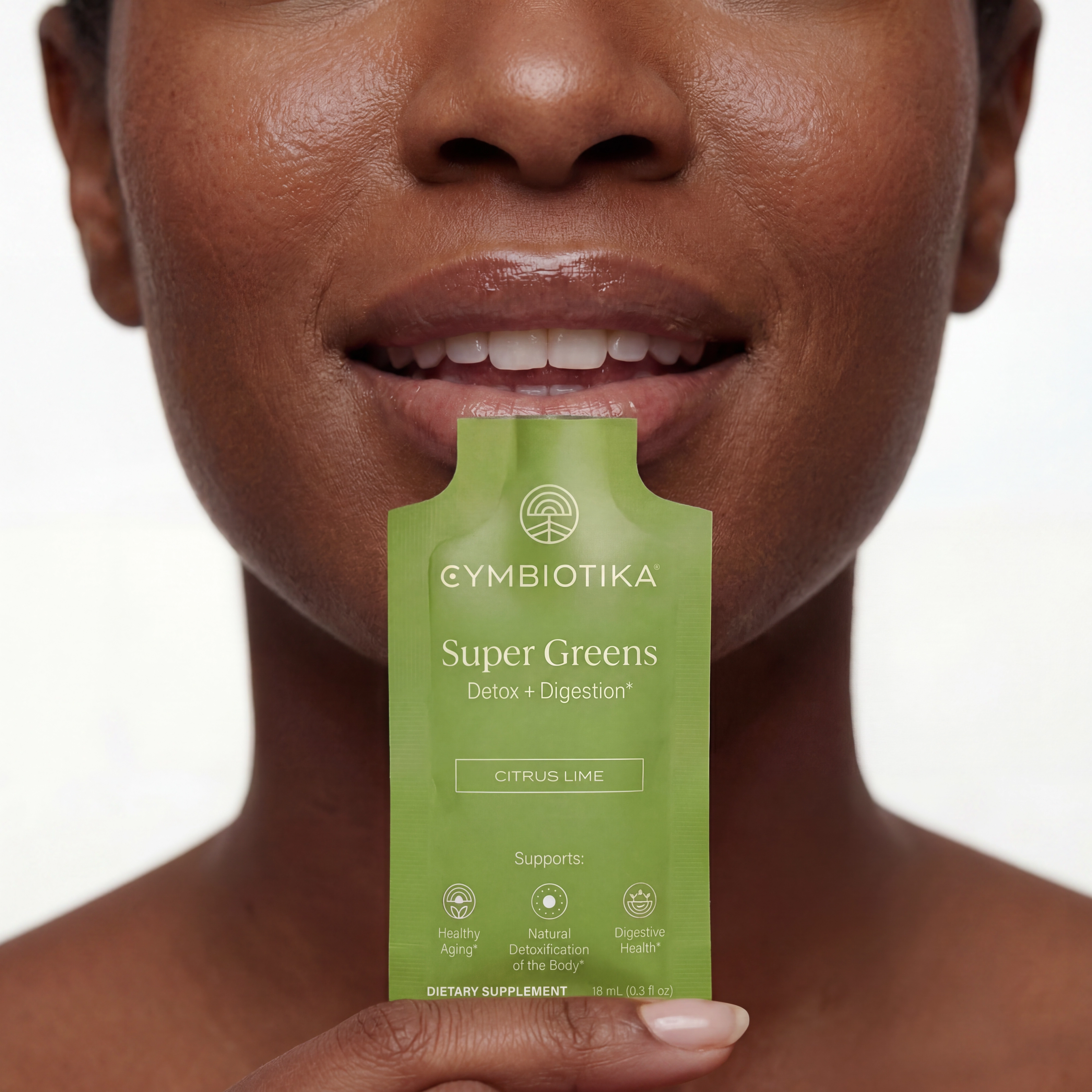 Person holding a Cymbiotika Super Greens Citrus Lime packet beneath their mouth.