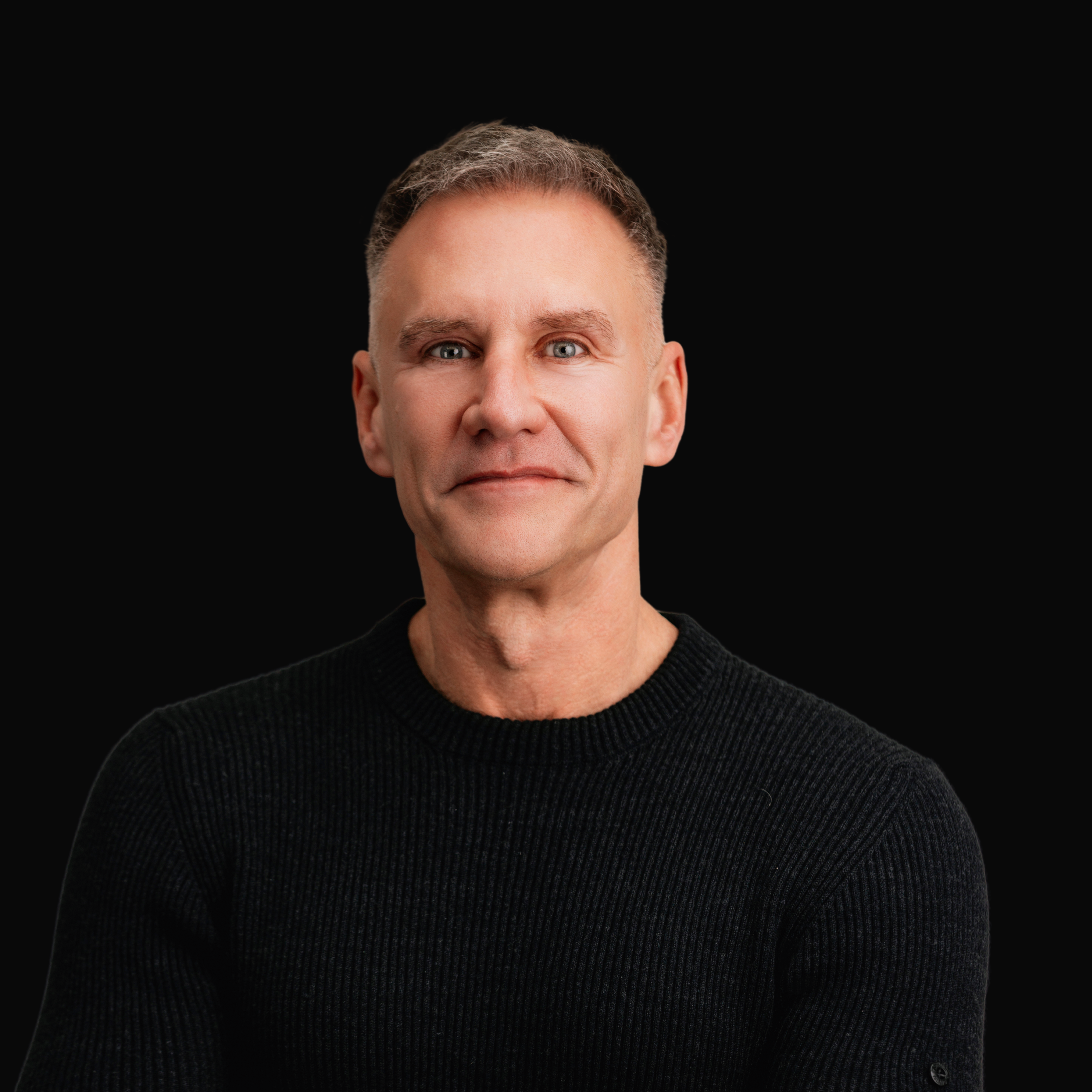 Portrait of a man in a black sweater against a black background, used in the Gary Brecka Protocol section.