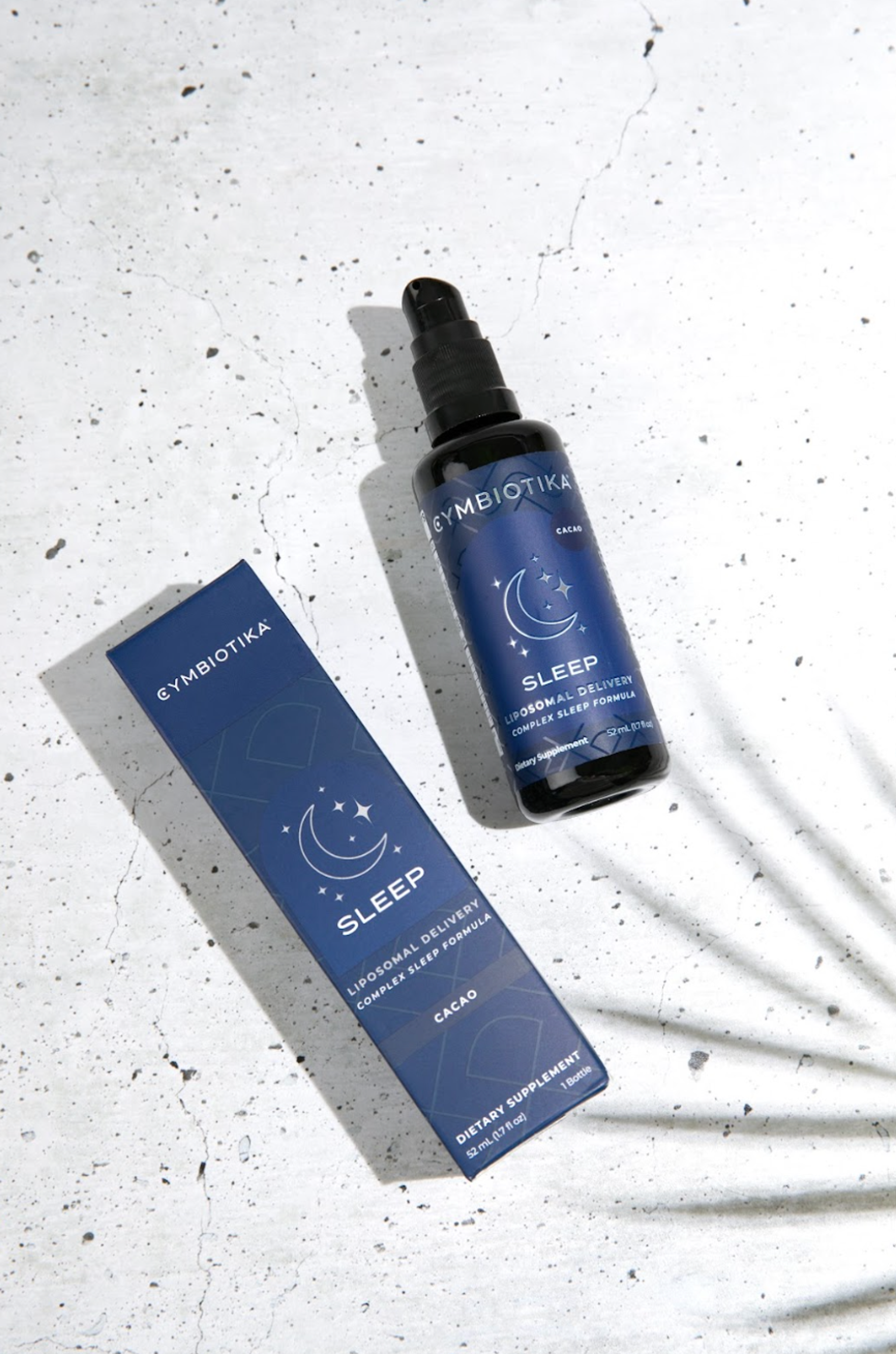 Cymbiotika Liposomal Sleep cacao bottle and box on a speckled white surface.