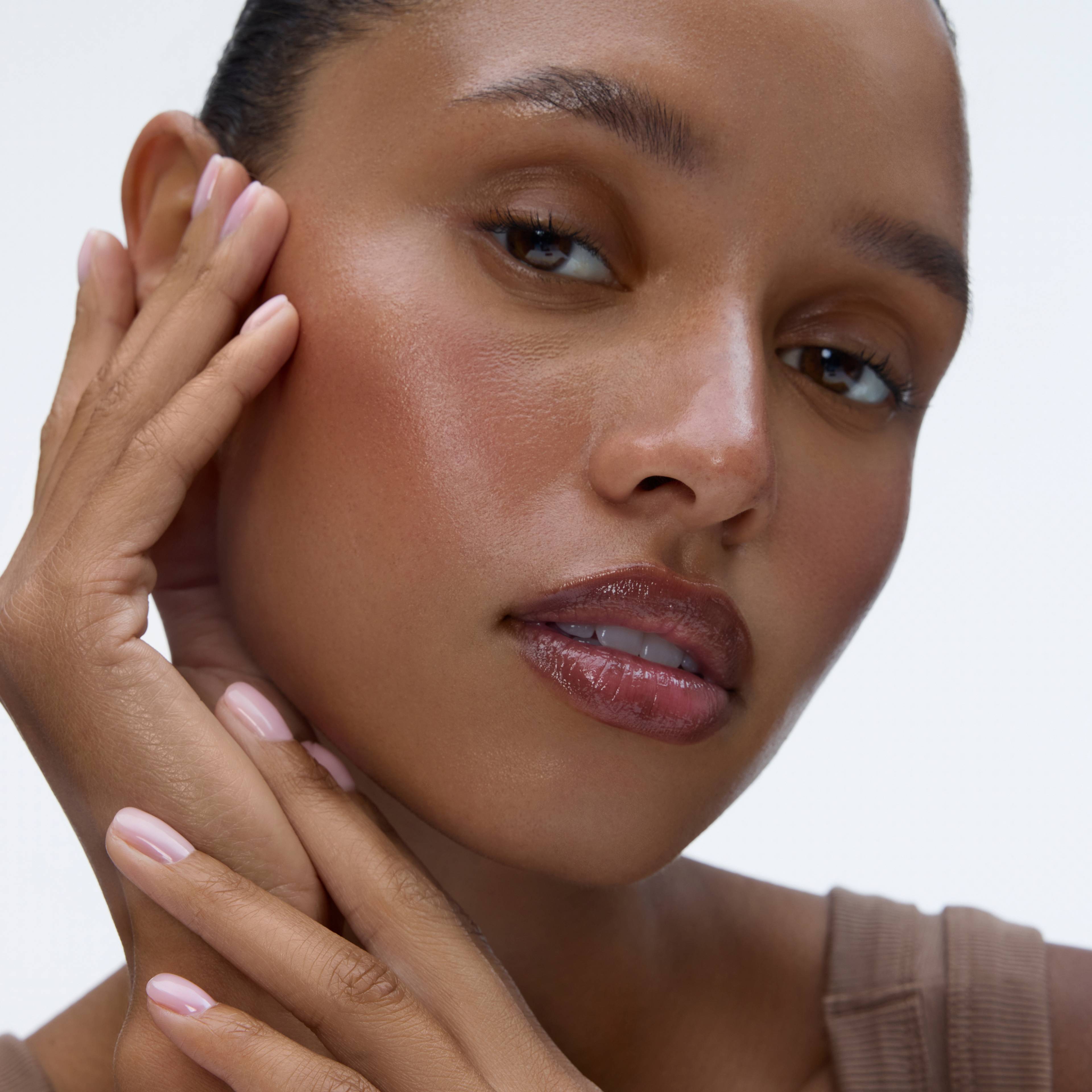 Close-up portrait of a woman gently touching her cheek, illustrating the beauty-focused product section.