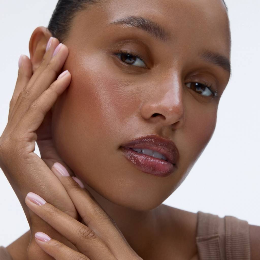 Close-up portrait of a woman gently touching her cheek, illustrating the beauty-focused product section.