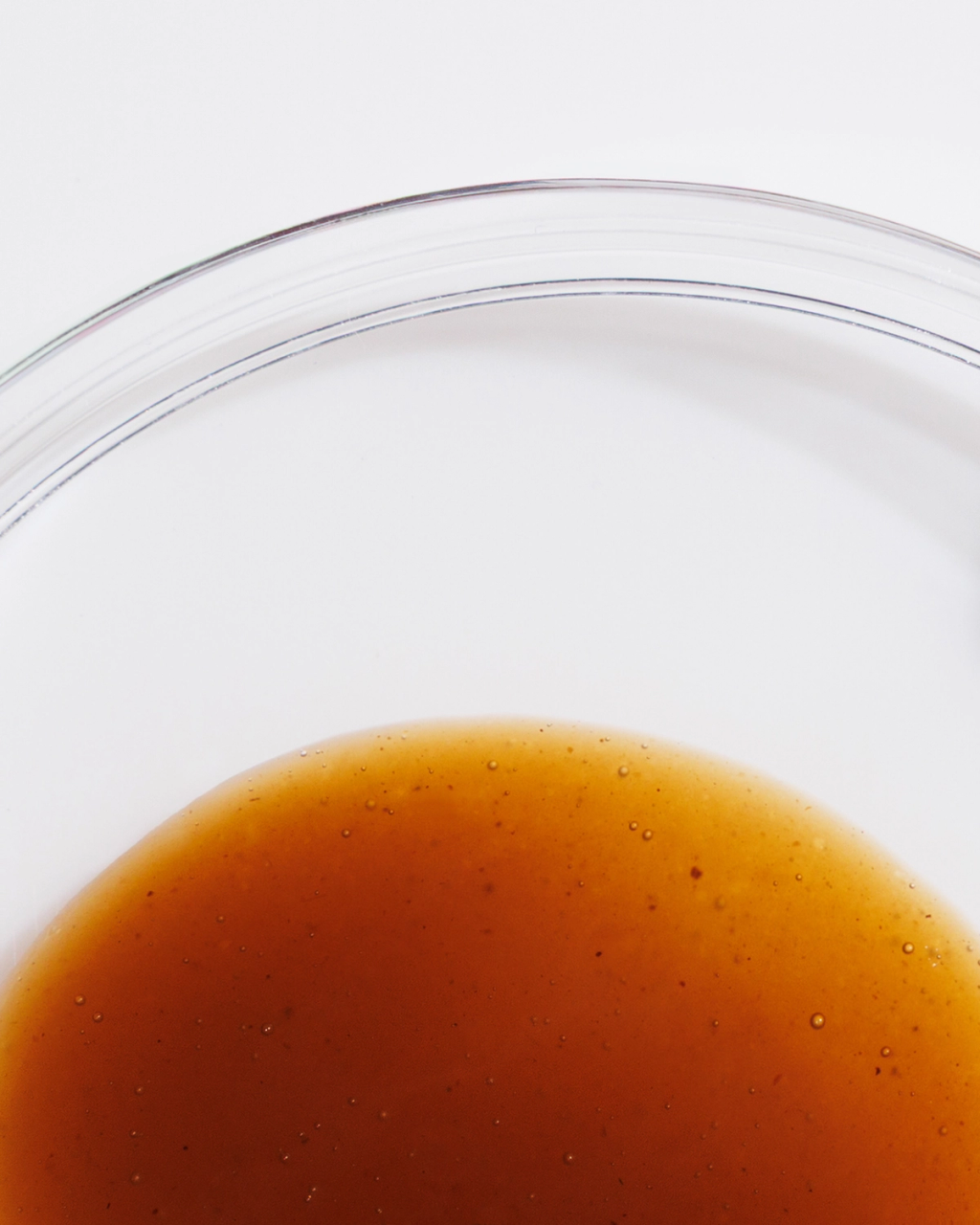 Close-up of amber liquid with small bubbles beneath curved transparent lines.