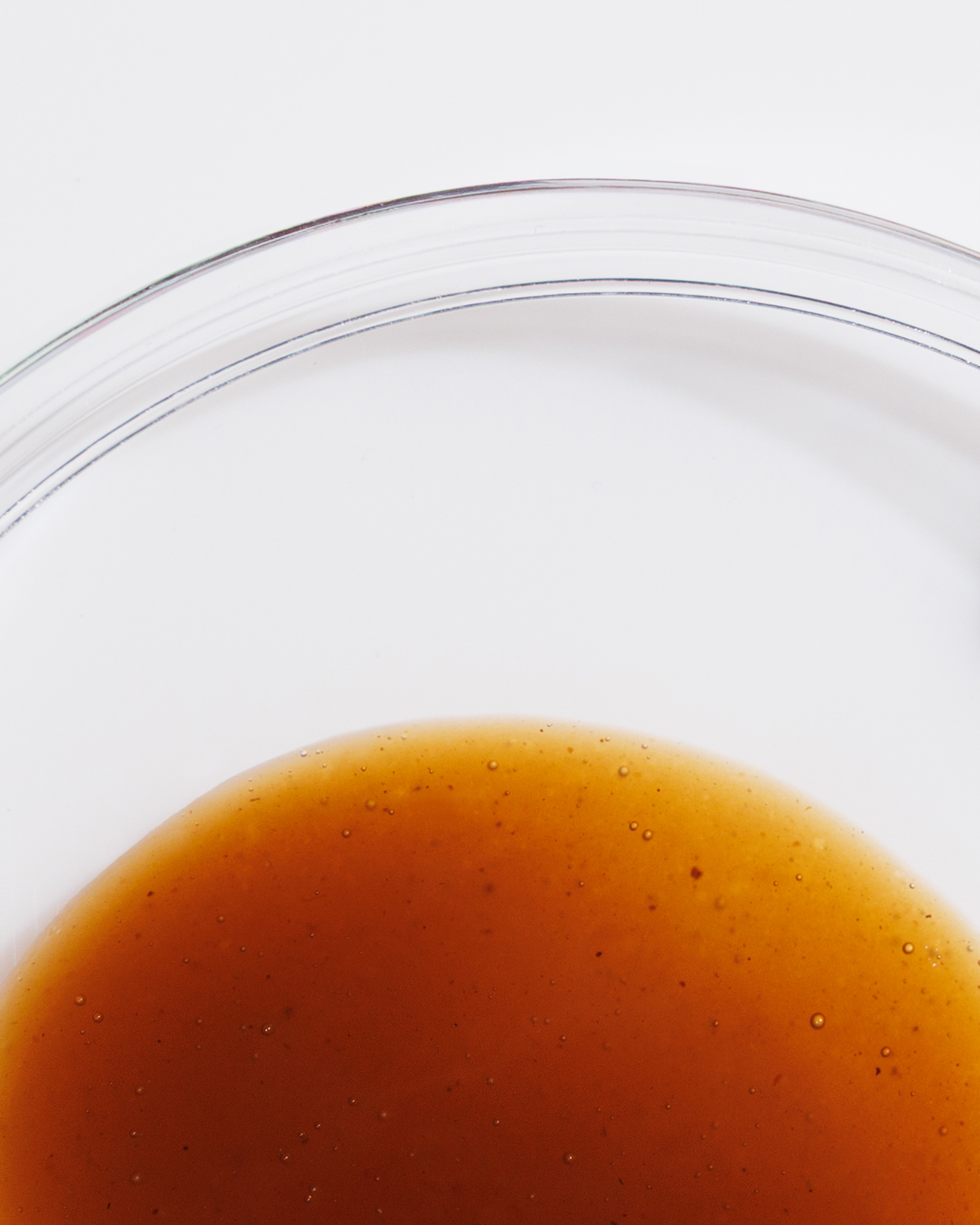 Close-up of amber liquid with small bubbles beneath curved transparent lines.