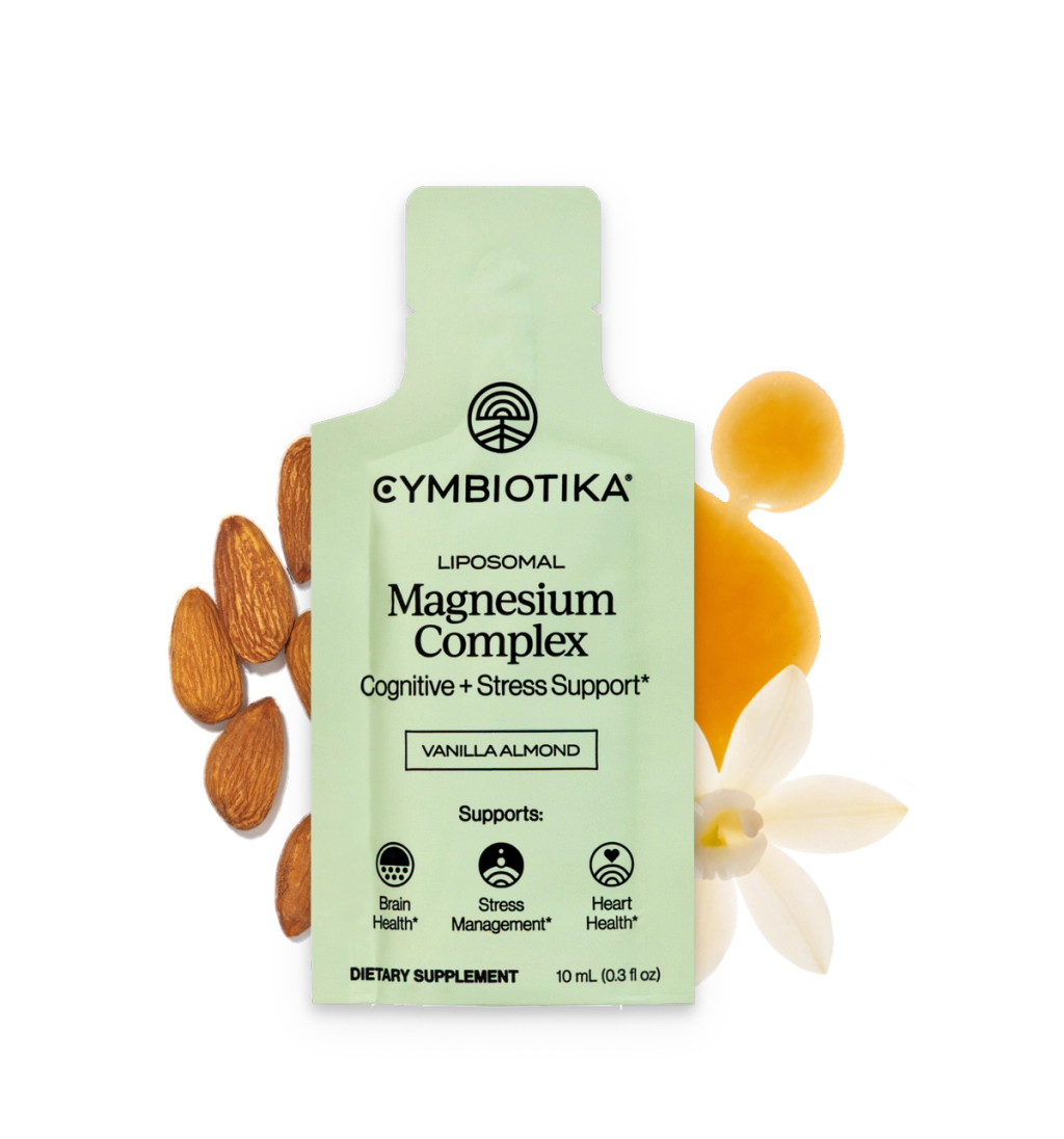 Cymbiotika Liposomal Magnesium Complex packet labeled Vanilla Almond, surrounded by almonds, a pale flower, and a round yellow object.