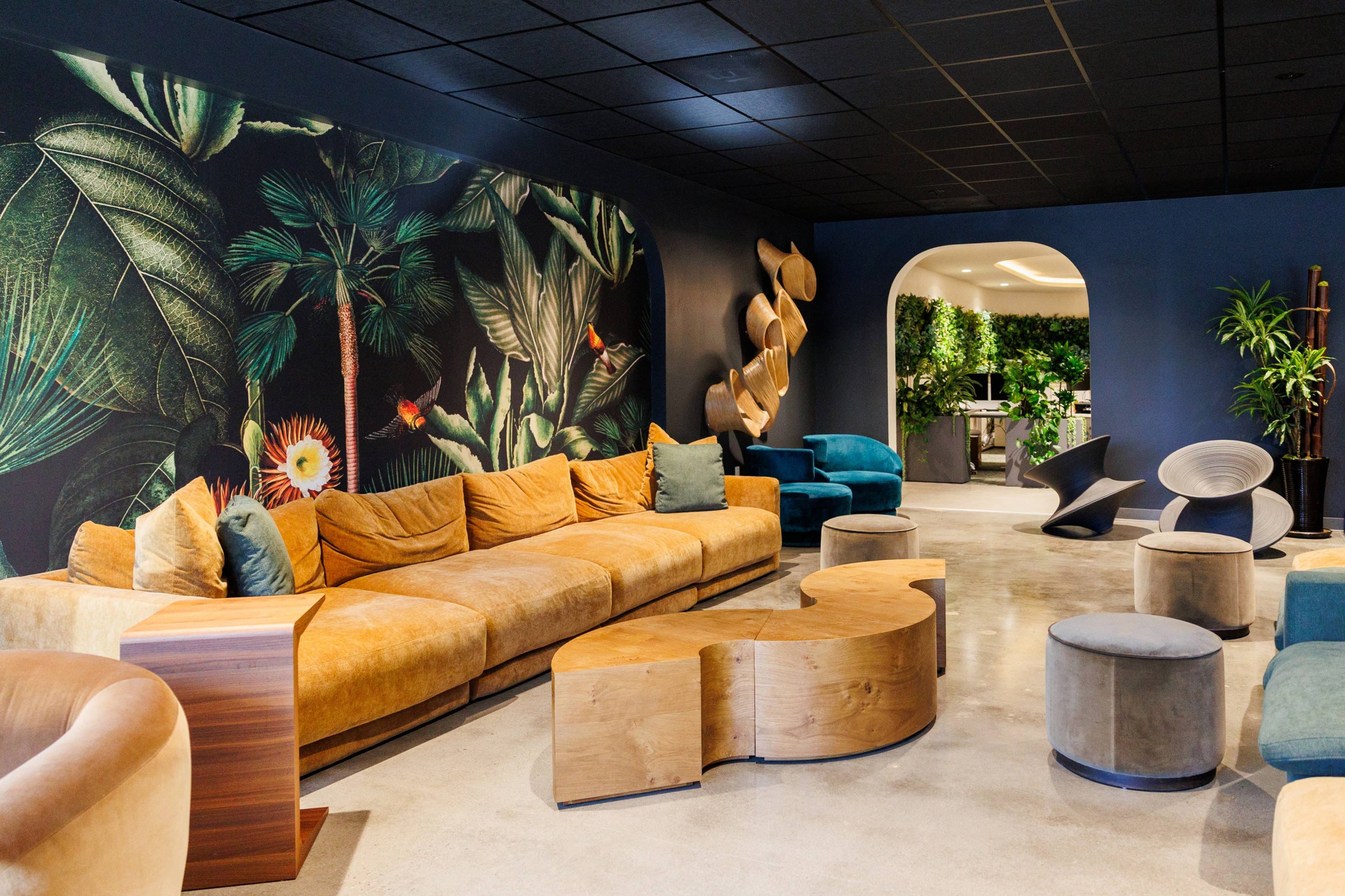 Office lounge with a long sofa and a tropical mural