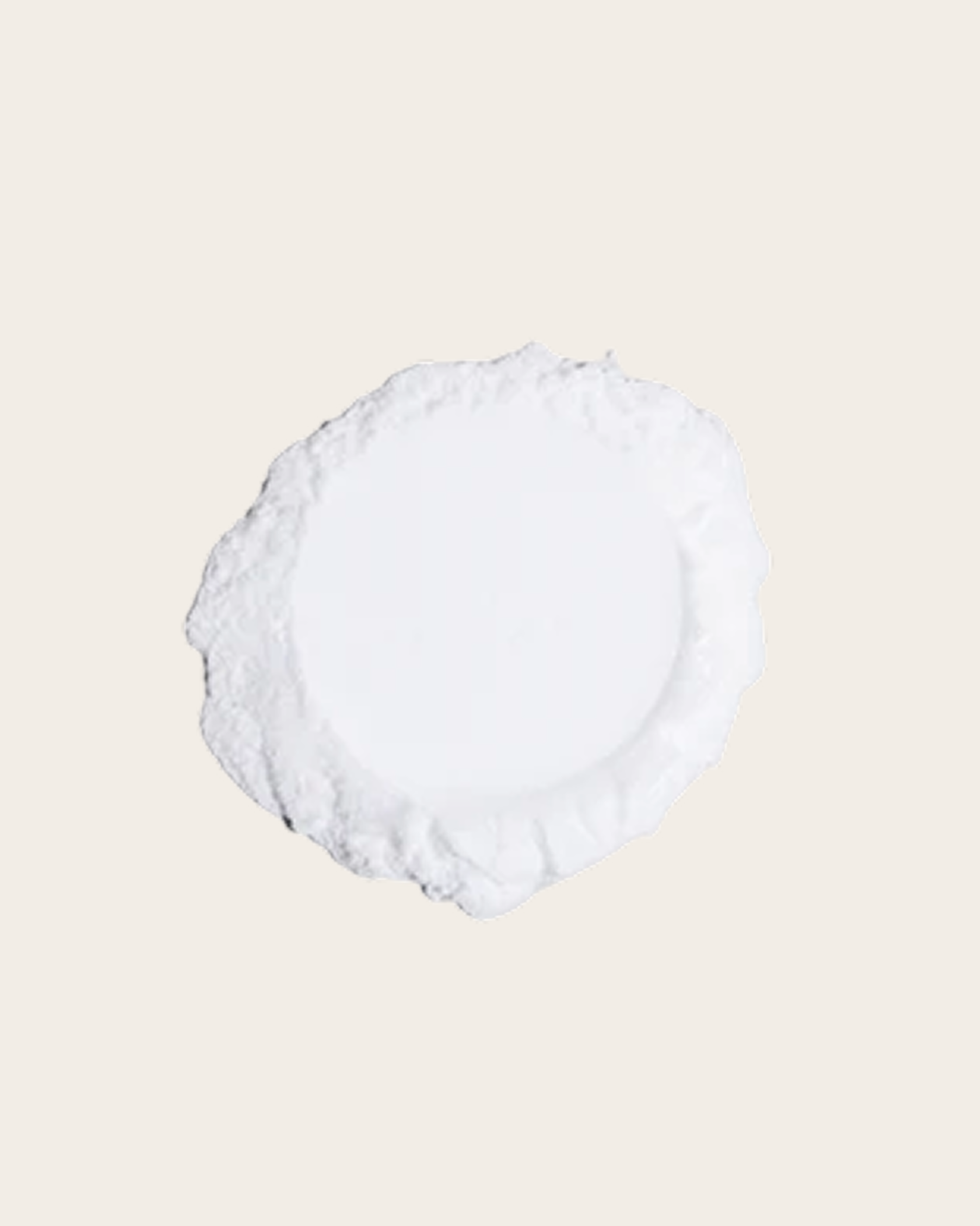 A round mound of white powder with an uneven edge against a pale beige background.