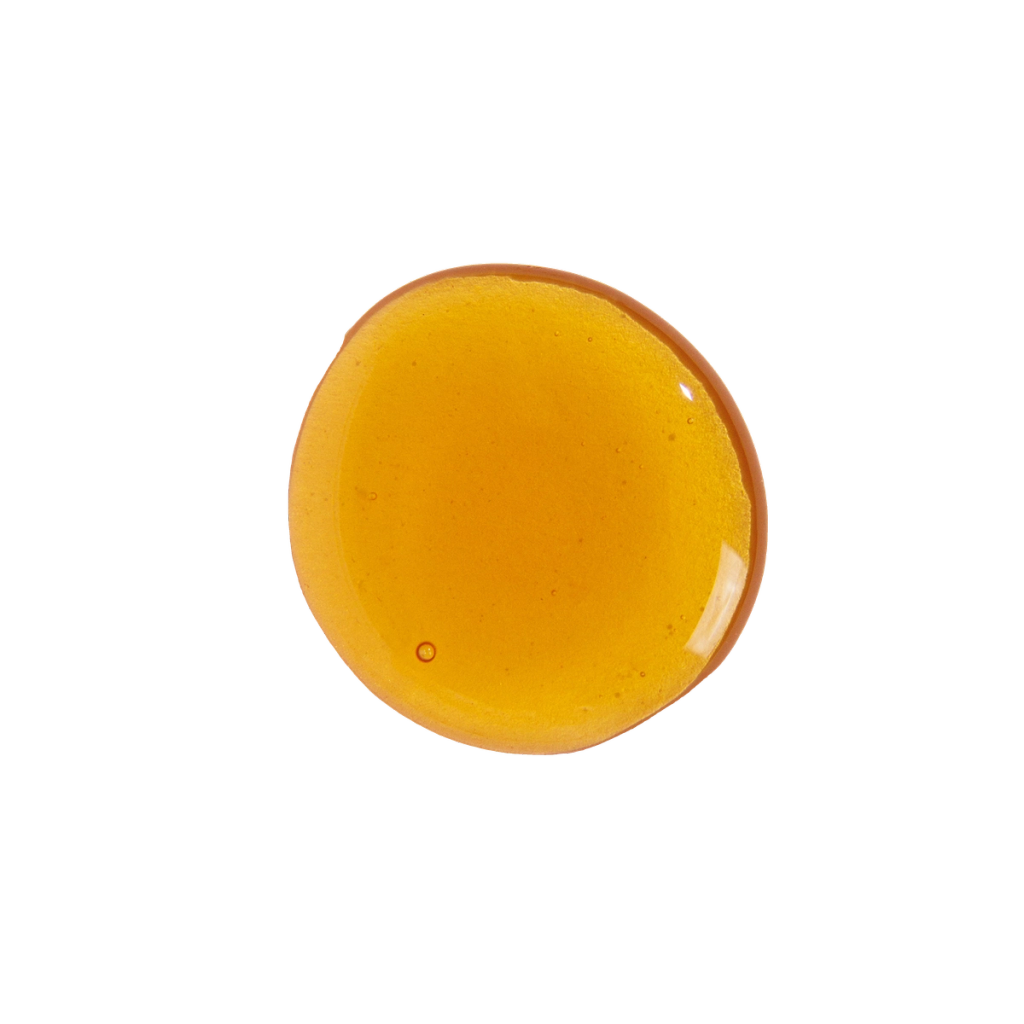 Glossy, round pool of amber-gold liquid with a few small bubbles.