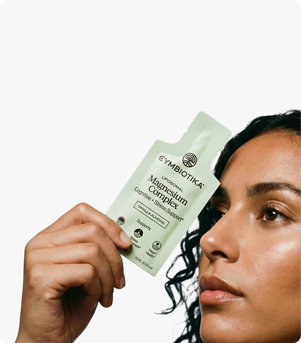 Woman holding a Cymbiotika Liposomal Magnesium Complex packet beside her face