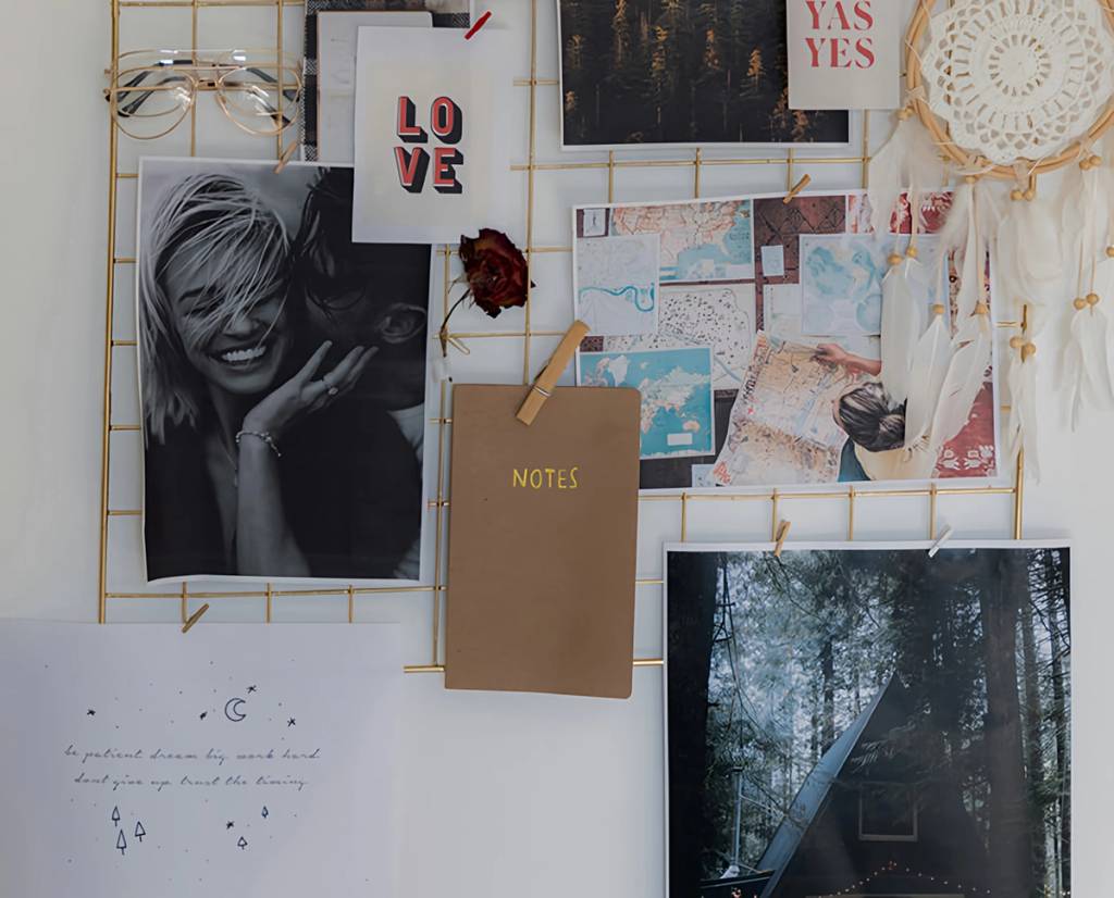 Wire inspiration board with photos, maps, notes, a dreamcatcher, and “LOVE” and “YAS YES” cards.