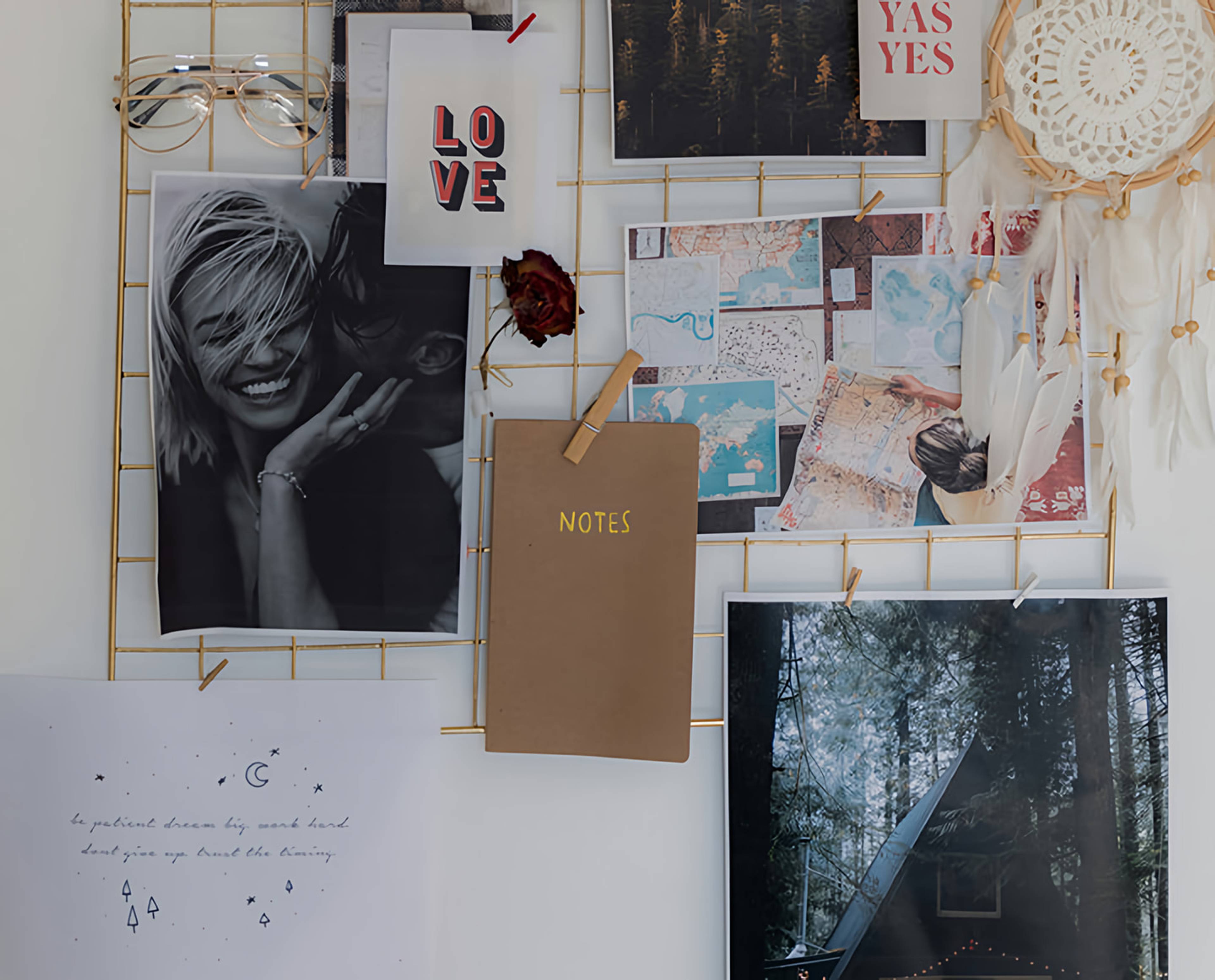 Wire inspiration board with photos, maps, notes, a dreamcatcher, and “LOVE” and “YAS YES” cards.