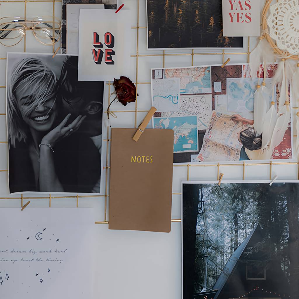 Wire inspiration board with photos, maps, notes, a dreamcatcher, and “LOVE” and “YAS YES” cards.