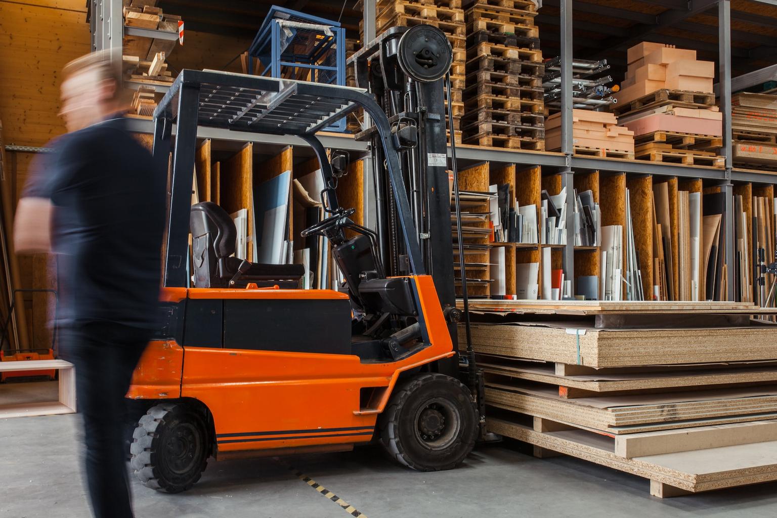 Image of a person walking by a warehouse room with trolley and item stock.