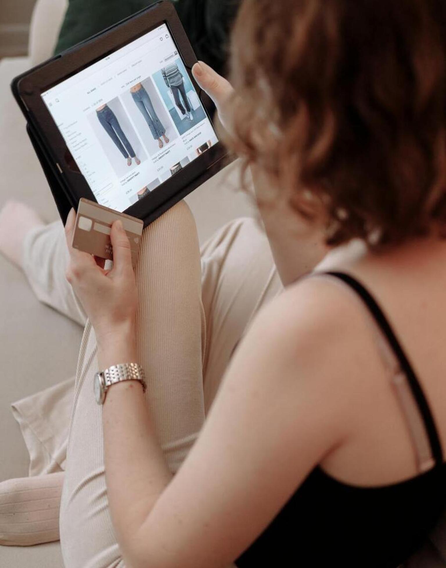 Women purchasing clothes on a tablet through an eCommerce website with credit card.