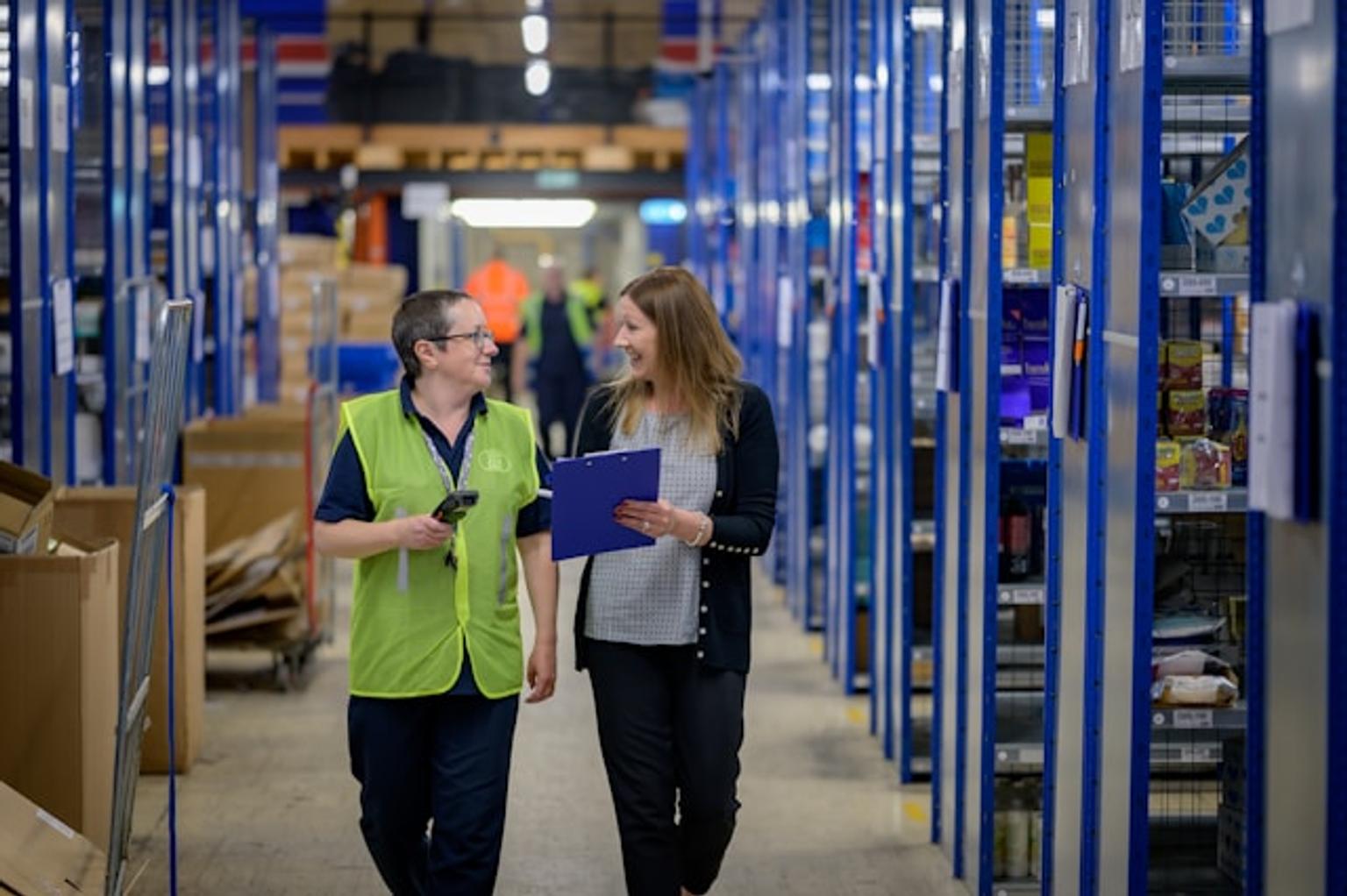 People talking in a fulfilment center confidently while smiling at each other