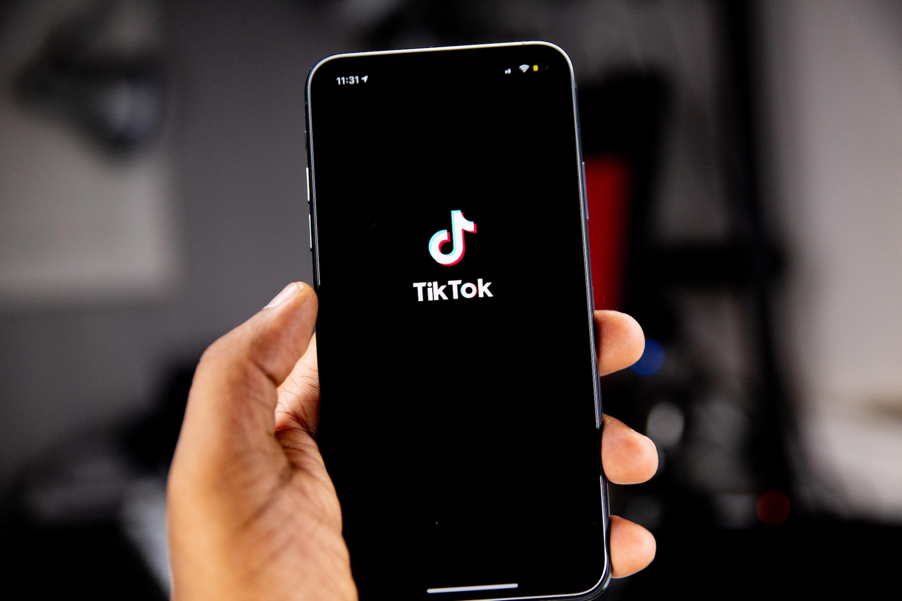 A person holding a smartphone while TikTok is opening.
