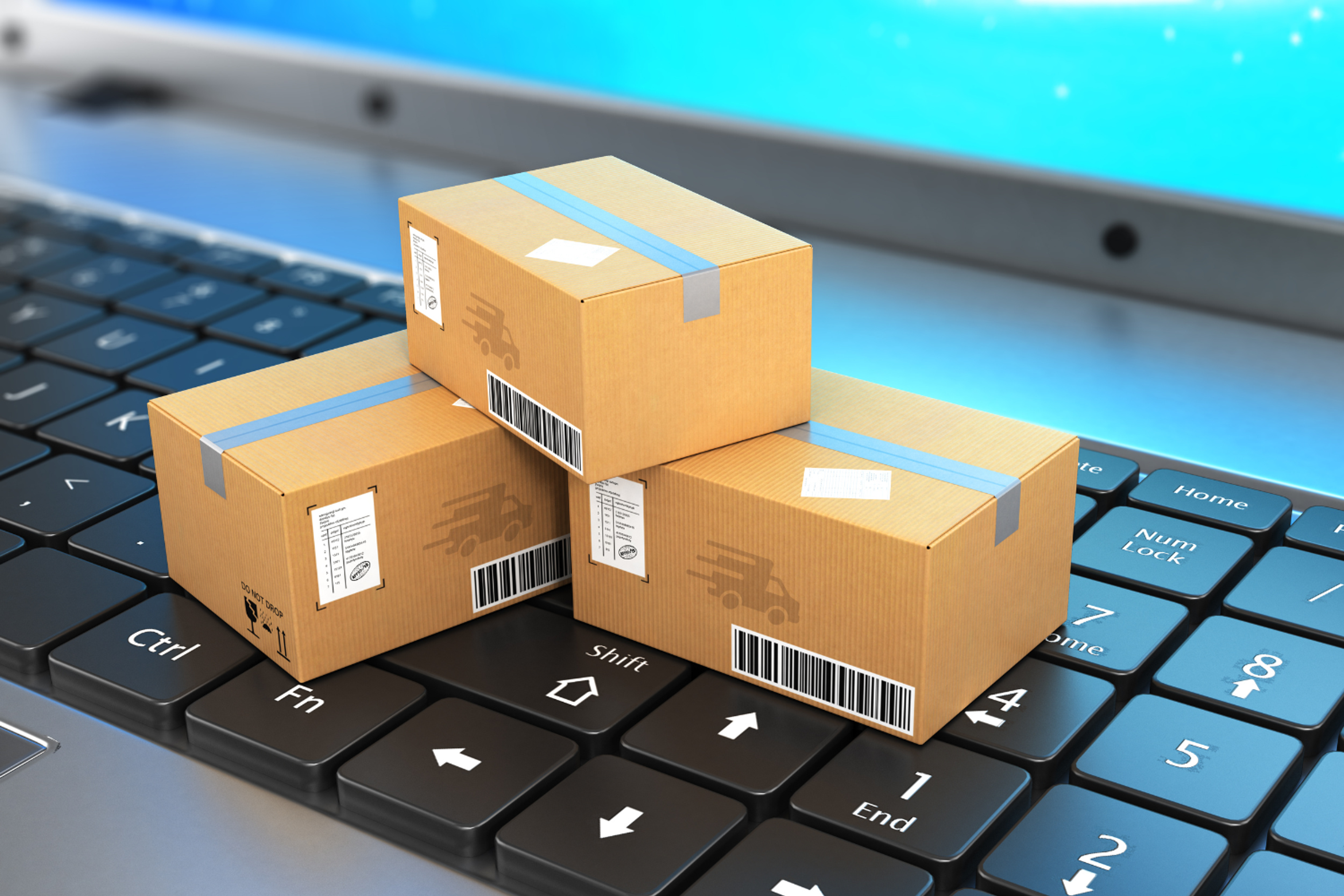 An image of miniature shipment boxes placed on a laptop keyboard