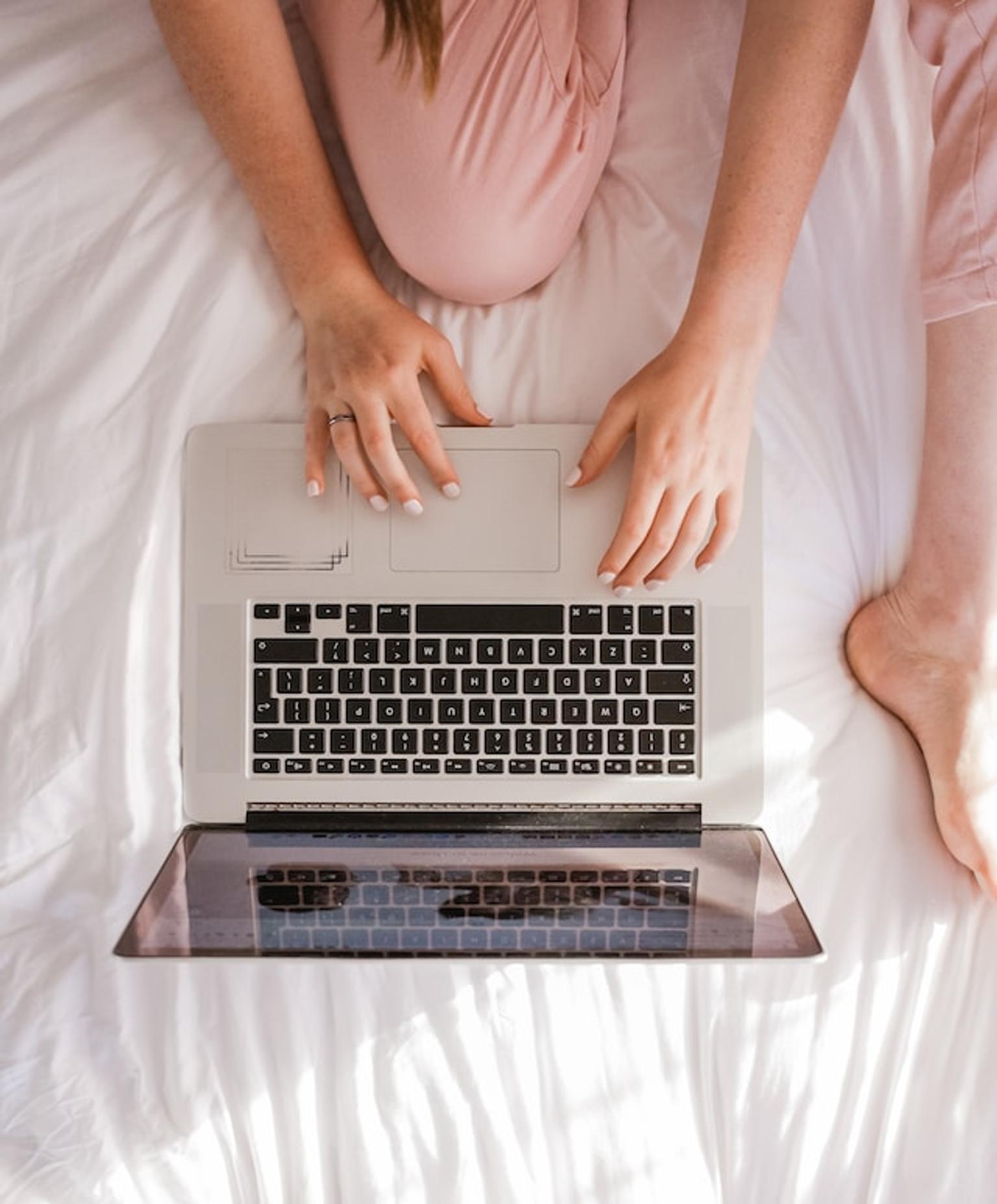 Person searching on web through a laptop in the bed