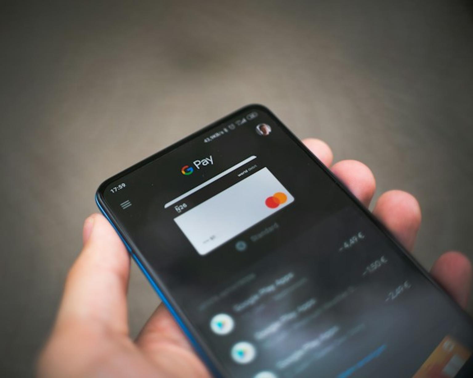 Person holding an Android smartphone with Google Pay profile.