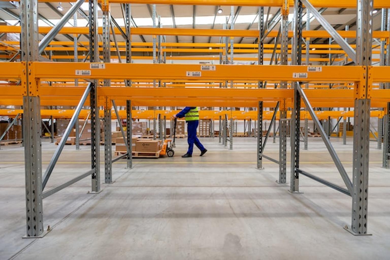 Person moving inventory in a warehouse on a trolley.