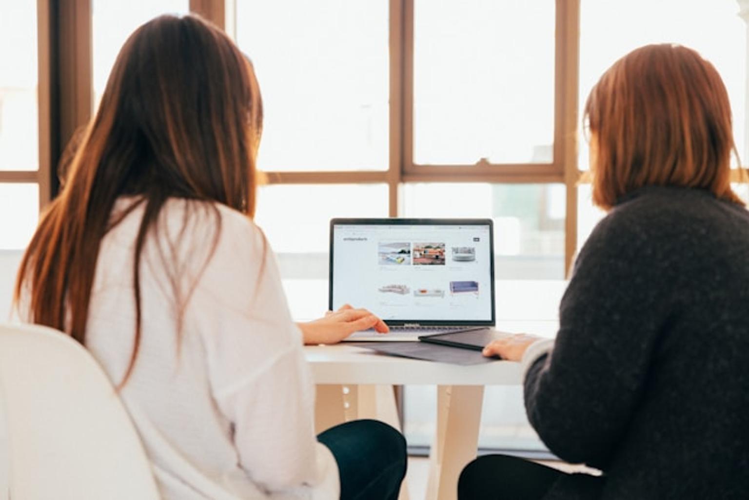 Two people browsing an online private label storefront on a computer in front of a desk.