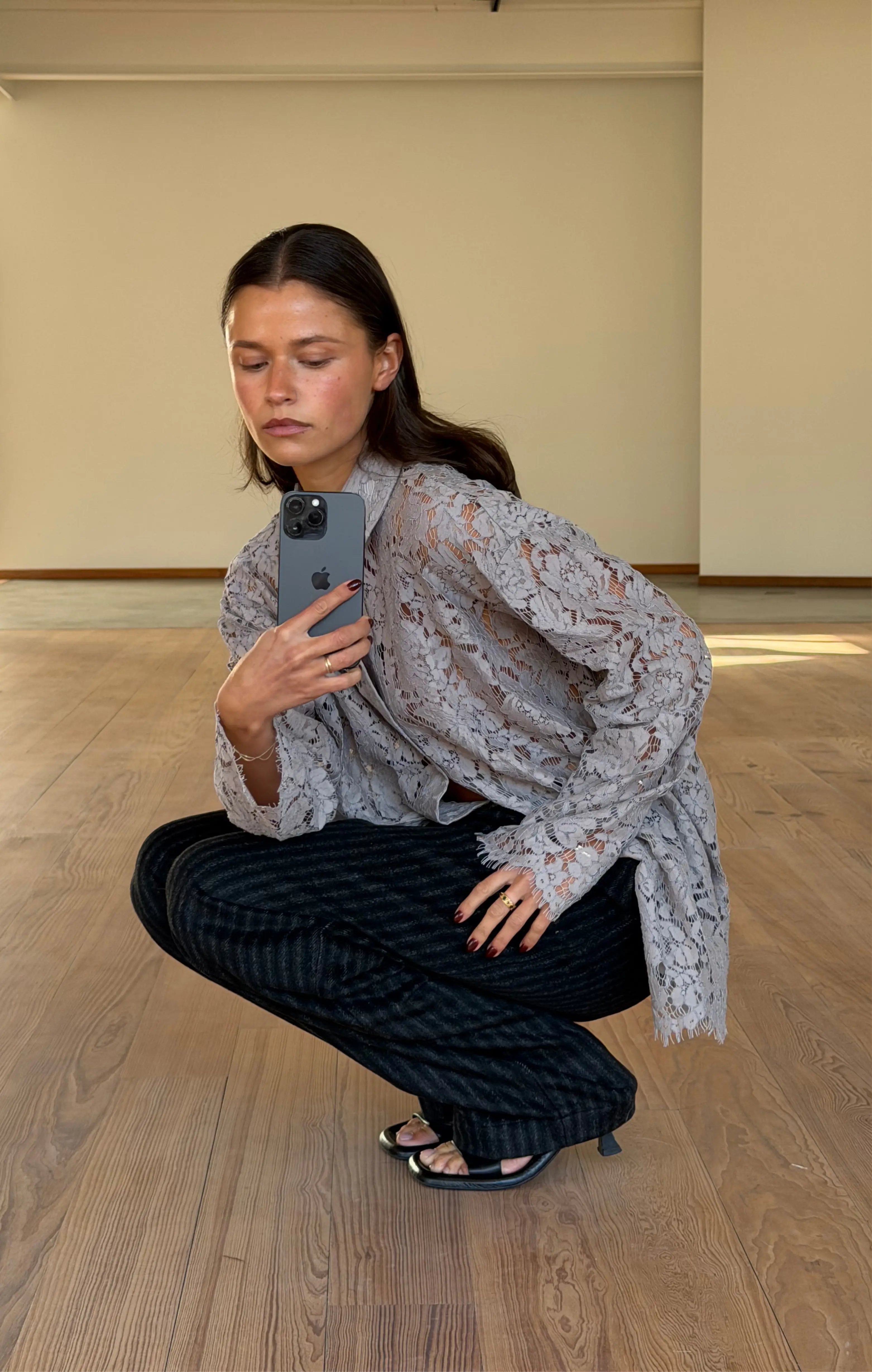 Vrouw maakt full body selfie binnen, grijze kanten top, gestreepte broek, zwarte sandalen