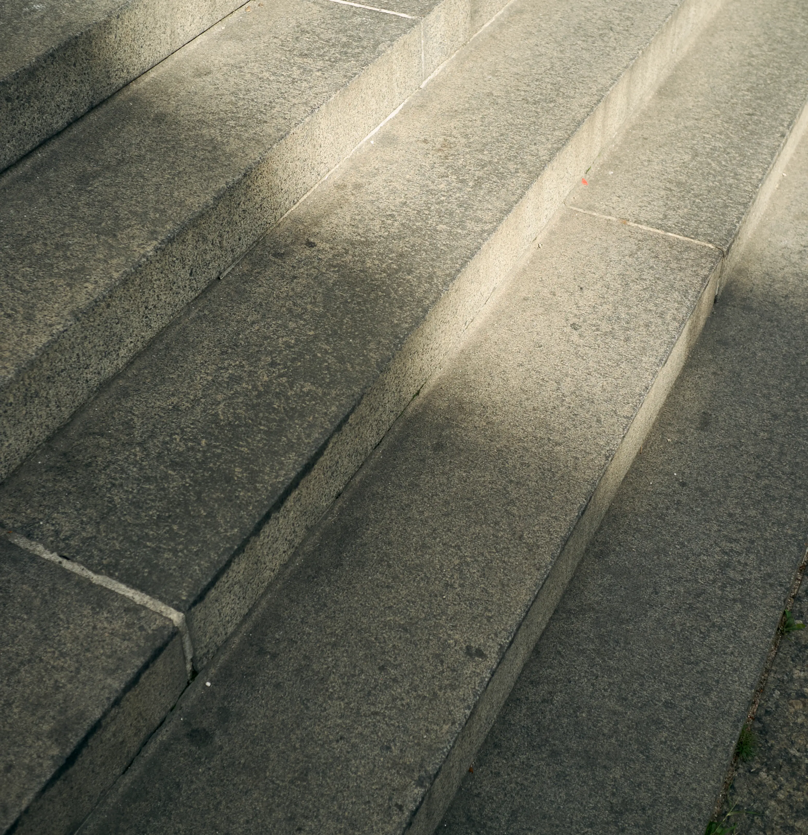 Close-up of speckled granite steps with diagonal sunlight and shadow.