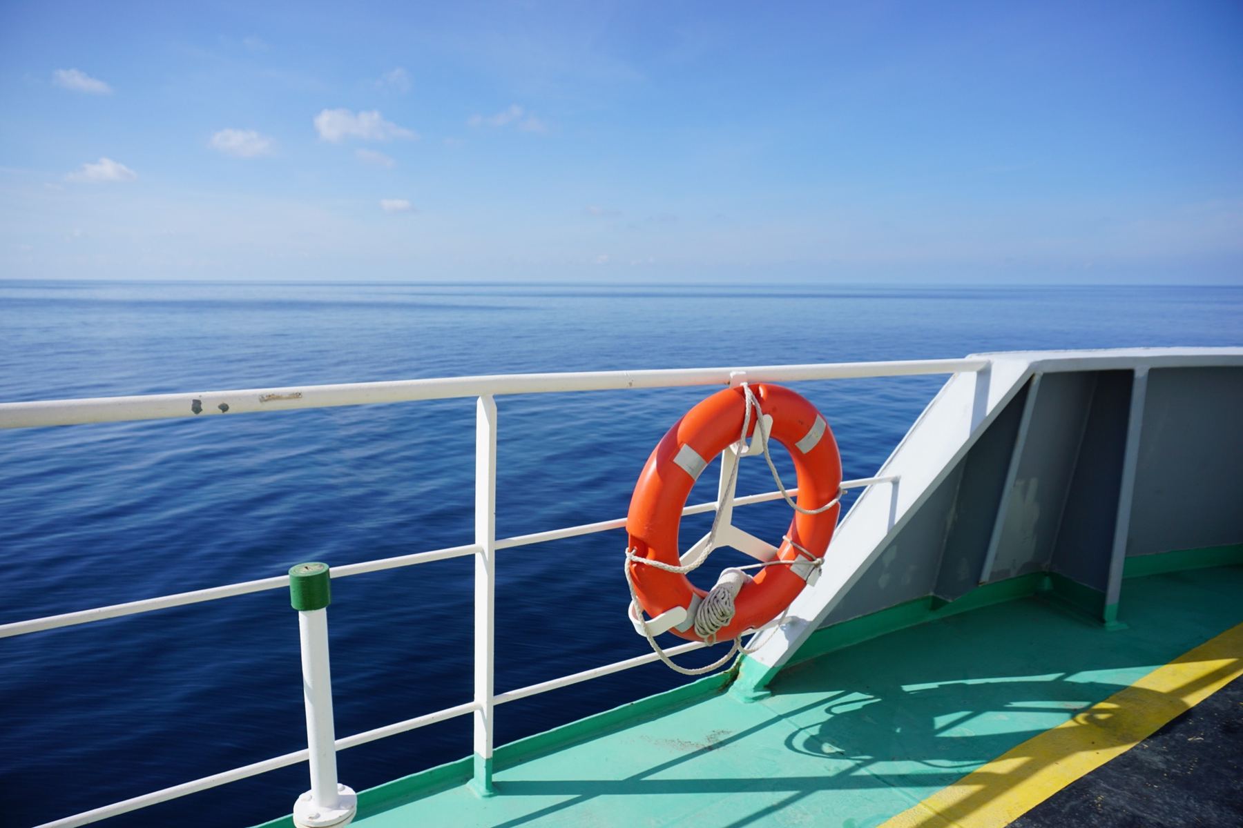 Orange lifebuoy on the deck rail of a vessel at sea