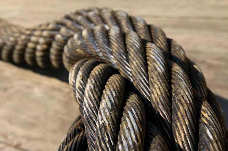 Close-up of heavy steel wire rope coiled on a timber deck