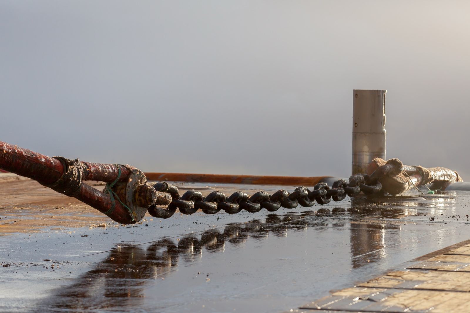 Anchor chain and mooring line made off on a wet vessel deck at first light