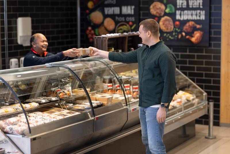 en ansatt gir en kunde en vare over disken