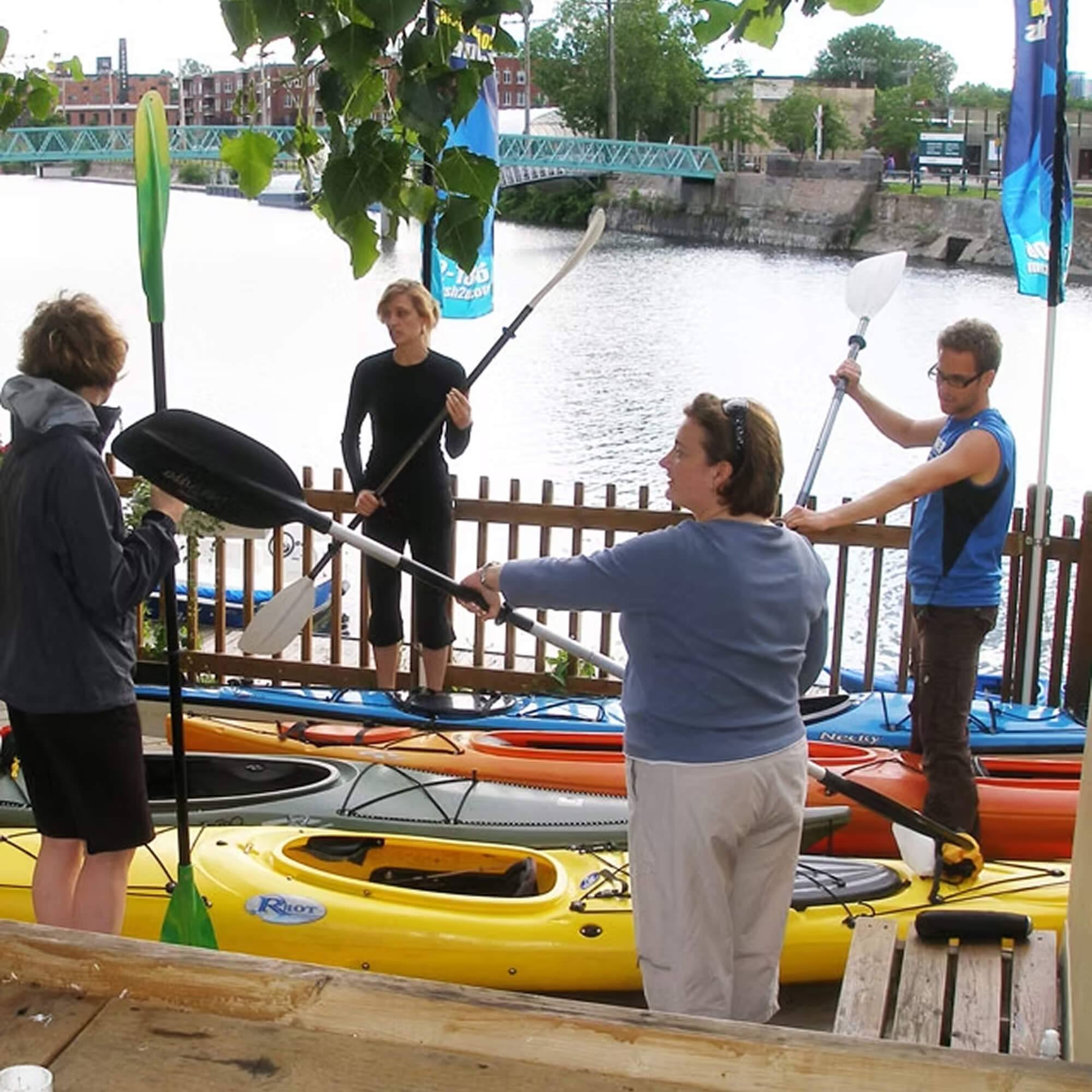 An instructor on the dock demonstrating proper paddling technique to a group of kayakers along the Lachine Canal in Montreal.