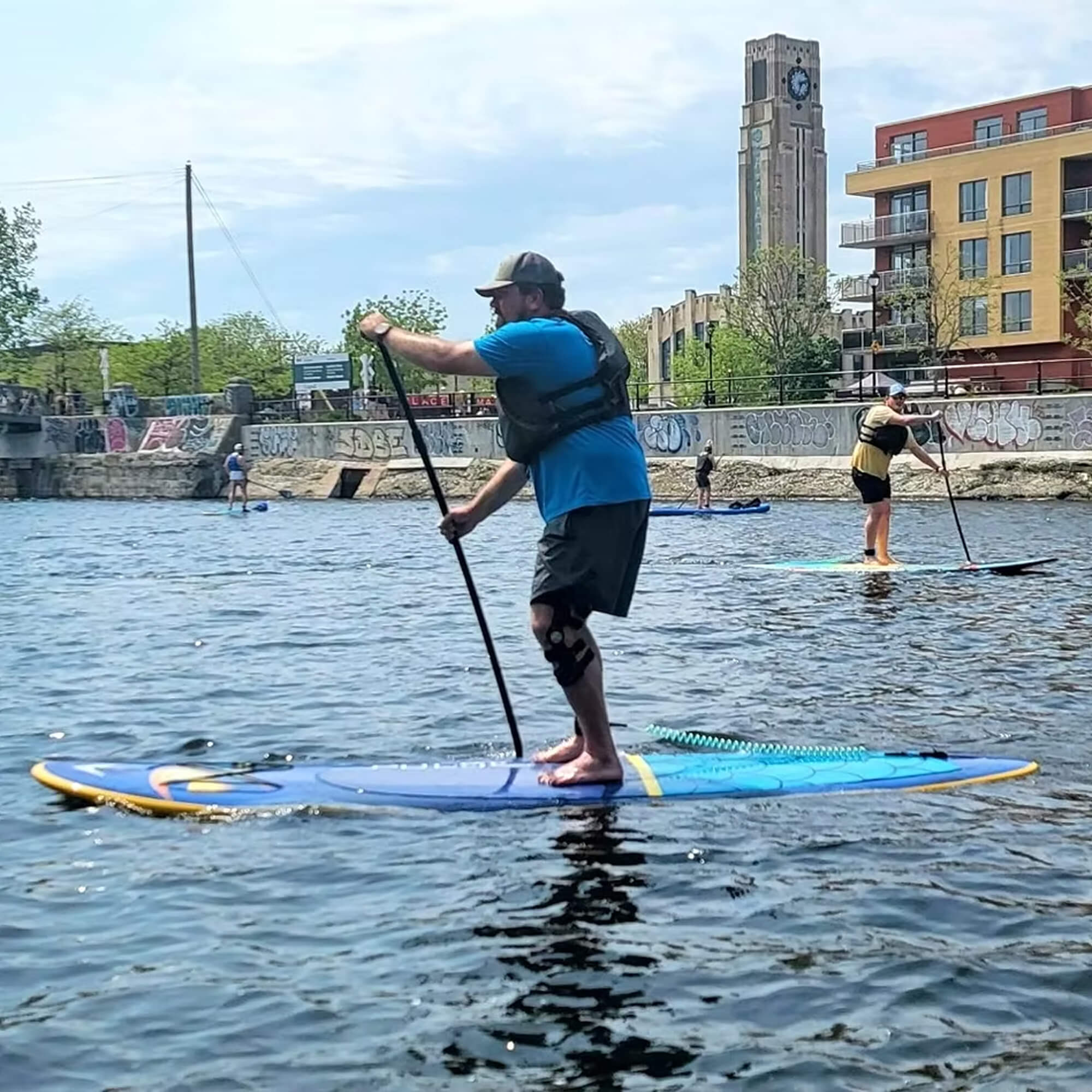 A person wearing a lifejacket practicing stand-up paddleboarding during an SUP lesson on the Lachine Canal in Montreal.