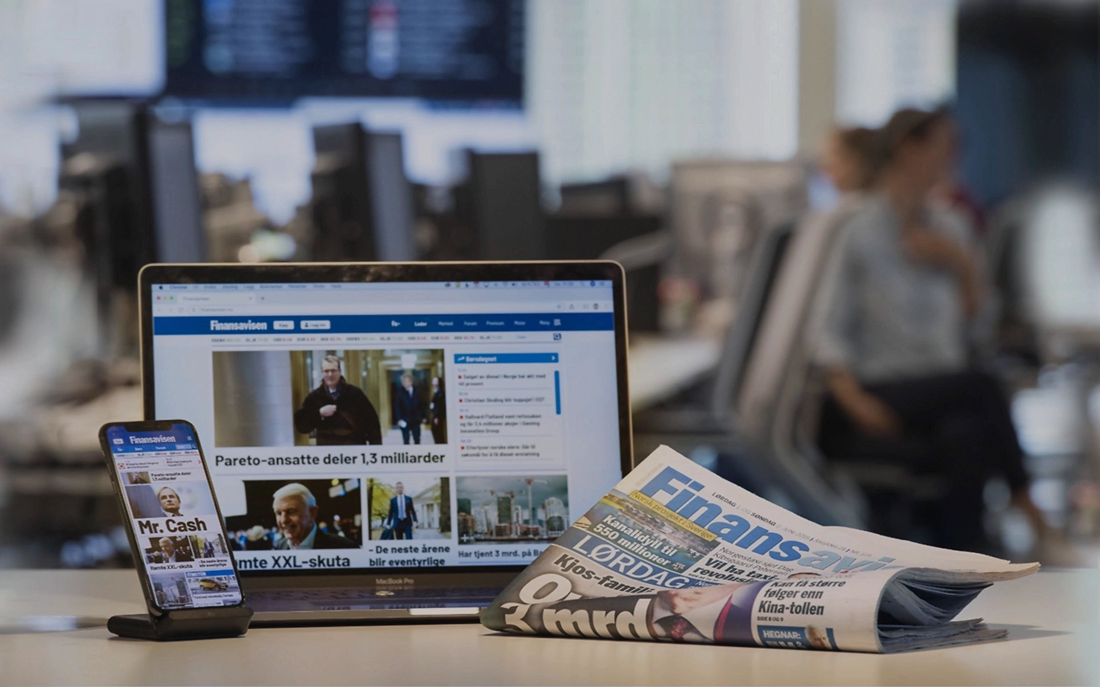Bilde av PC-skjerm med Finansavisen nettsiden, telefon og avis
