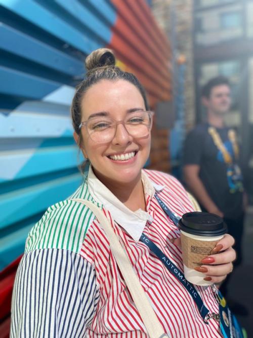 marguerite facing a camera and smiling with a cup of coffee in her left hand
